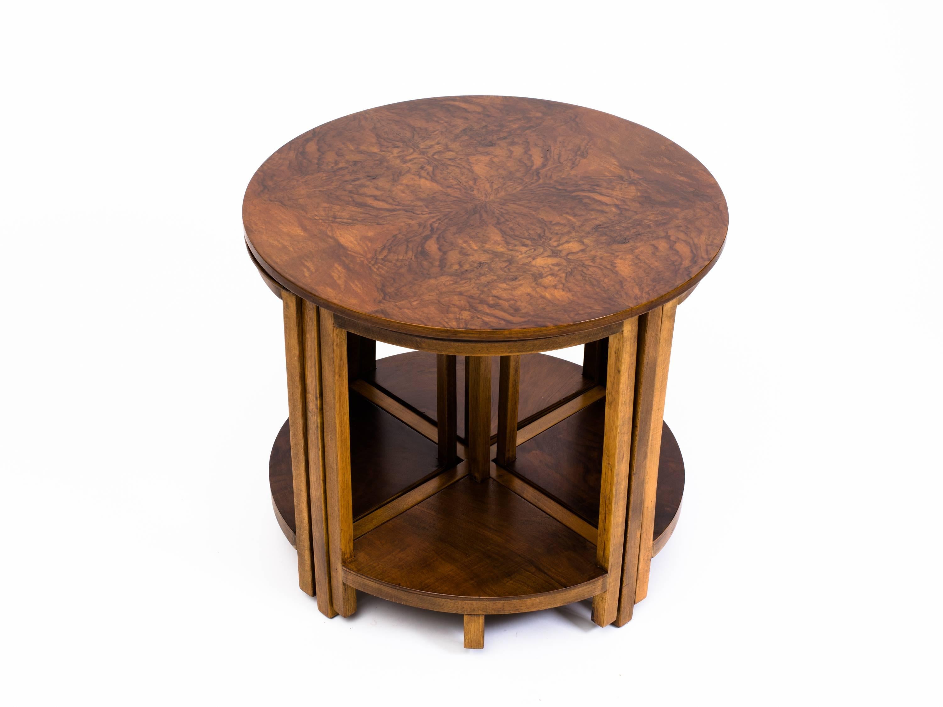 Machine Age walnut circular walnut burl end table with nesting tables. Four nesting tables each with unique grain to tops and shelves, pull-out from under table. 
In the style of Art Deco designer Donald Deskey, who designed all the interiors and