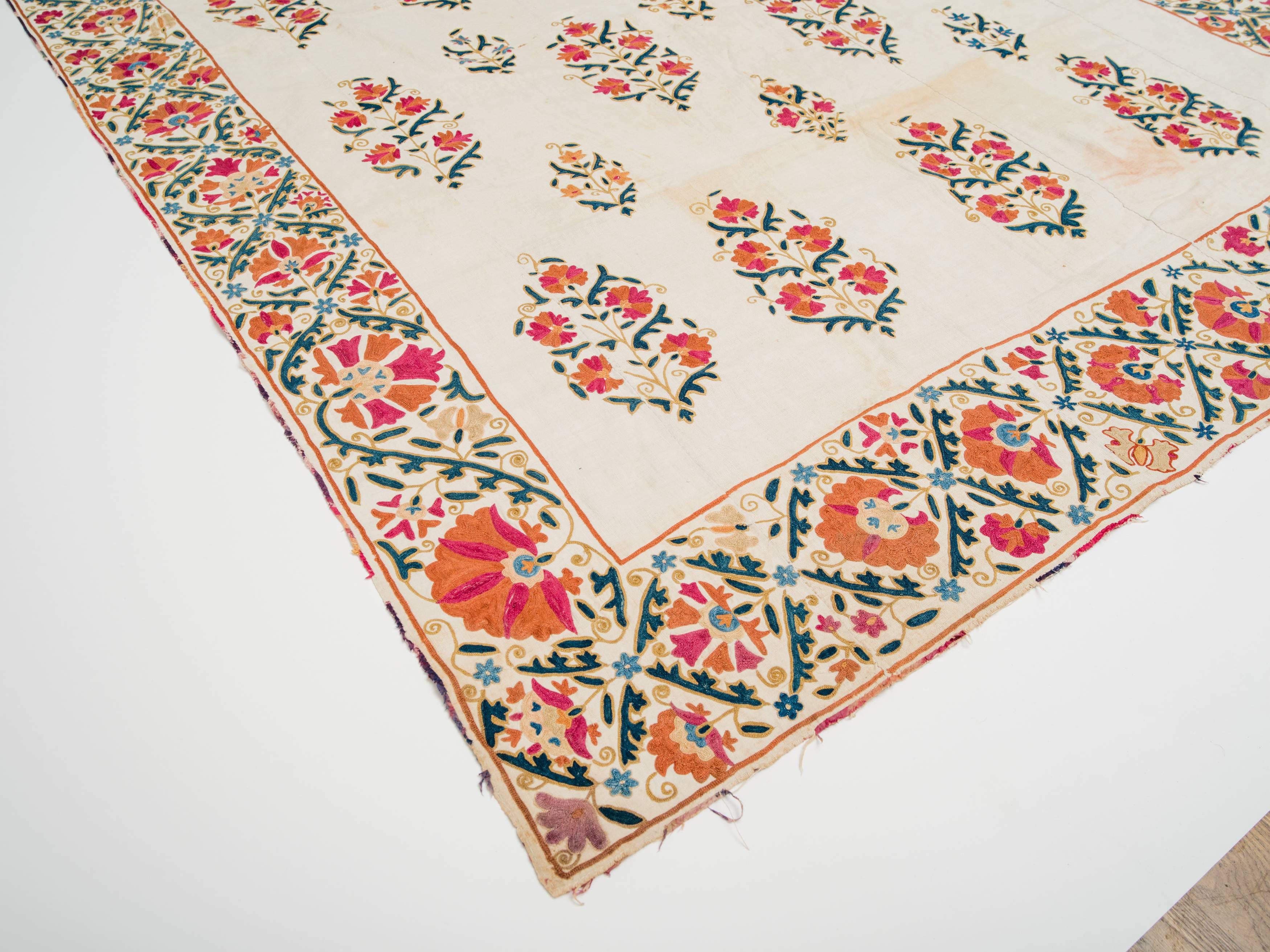Suzani du 19e siècle en lin filé à la main en Ouzbékistan, avec motif floral brodé en soie et bordure en ikat de soie. Le verso est recouvert d'un support en coton imprimé à la main.
 