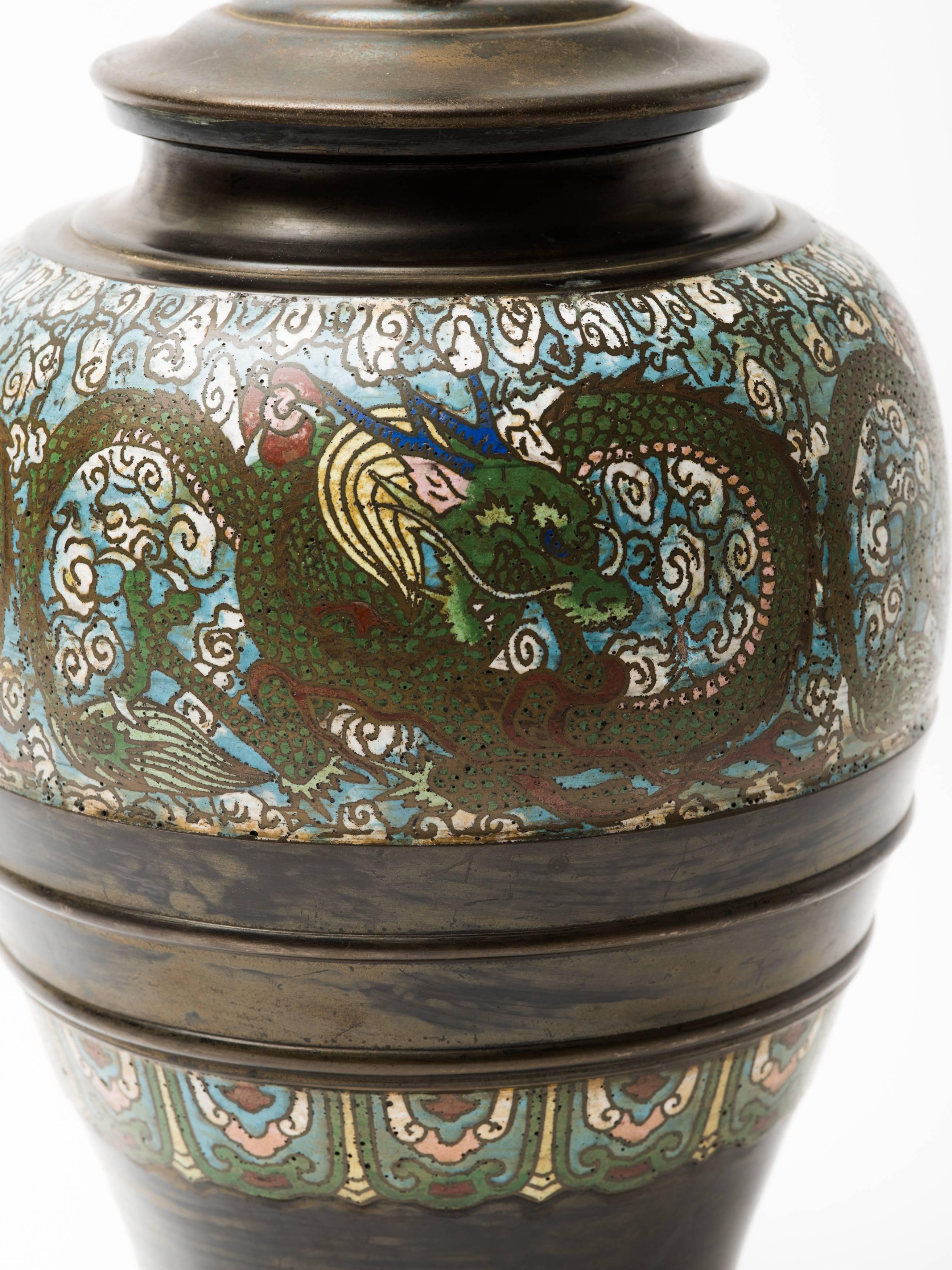 Bronze champlevé lamp with stylized dragon enameled cloisonné design surrounding and gorgeous patina. Mounted on hand-carved lacquered wood base, China, circa 1910-1920.