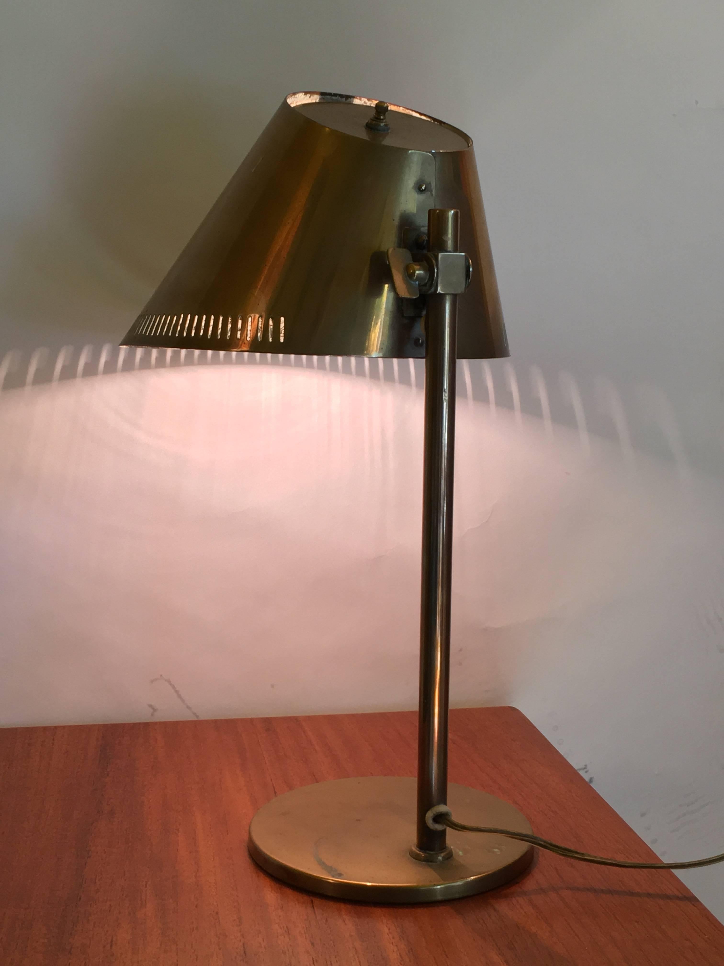 Tynell adjustable table or desk lamp, tubular and perforated brass. Cast iron base impressed Taito/9227. Inside of shade retains white enamel.Ornamental slits release heat and create light patterns. Made in Finland, circa 1958.