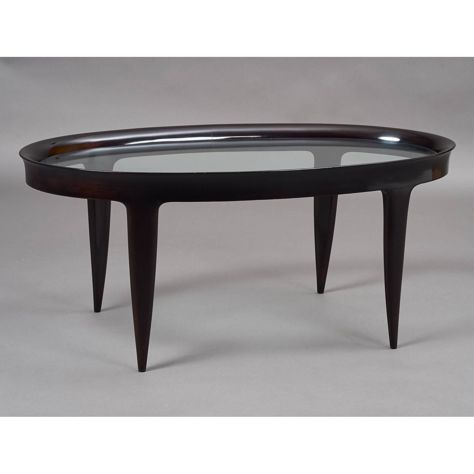 Elegant oval coffee or side table in the style of Gio Ponti,
stained wood with glass top inset in a beautifully carved frame
and tapered legs, Italy, 1950s.
Dimensions: 44 x 23.5 x 19 H.
        