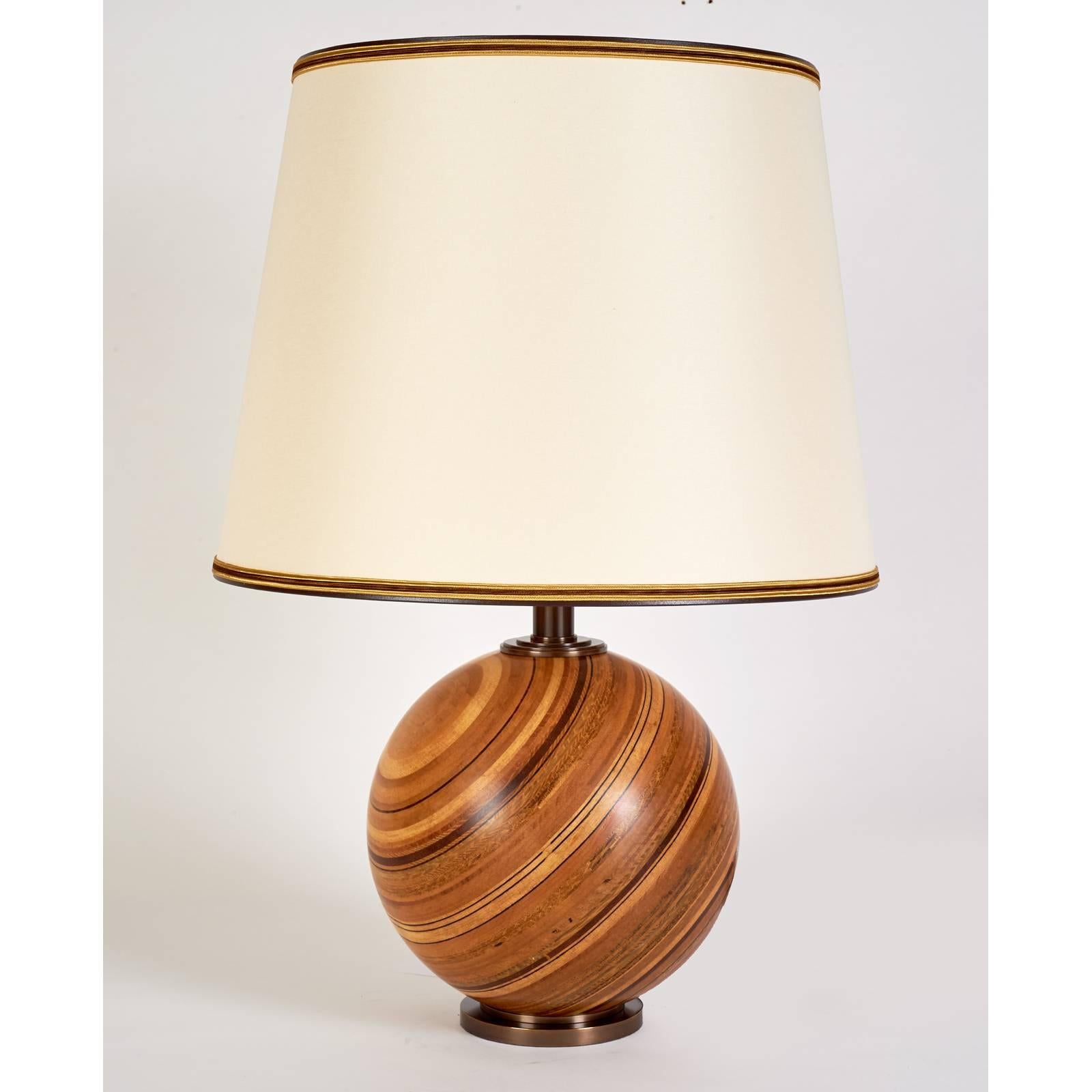 
France, 1960s.

Beautiful turned wood table lamp.
Multiple layers of different laminated woods creating a circular striped pattern.
Oxidized bronze mounts.

Measures: 18 diameter x 27 H.

Rewired for use in the U.S.A with two standard base
