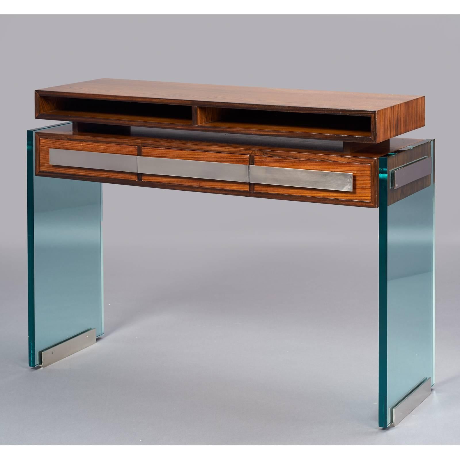 Roberto Rida (b. 1943).
A modernist console table in polished wood, raised on massive glass legs with nickeled bronze drawer pulls and mounts. Three drawers below, two storage niches above. Finished on all sides, may be used floating. Unique piece.