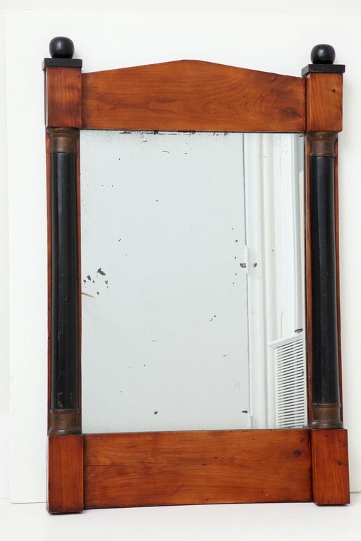 A 19th century German cherrywood and ebonized mirror of architectural form with old plate glass.