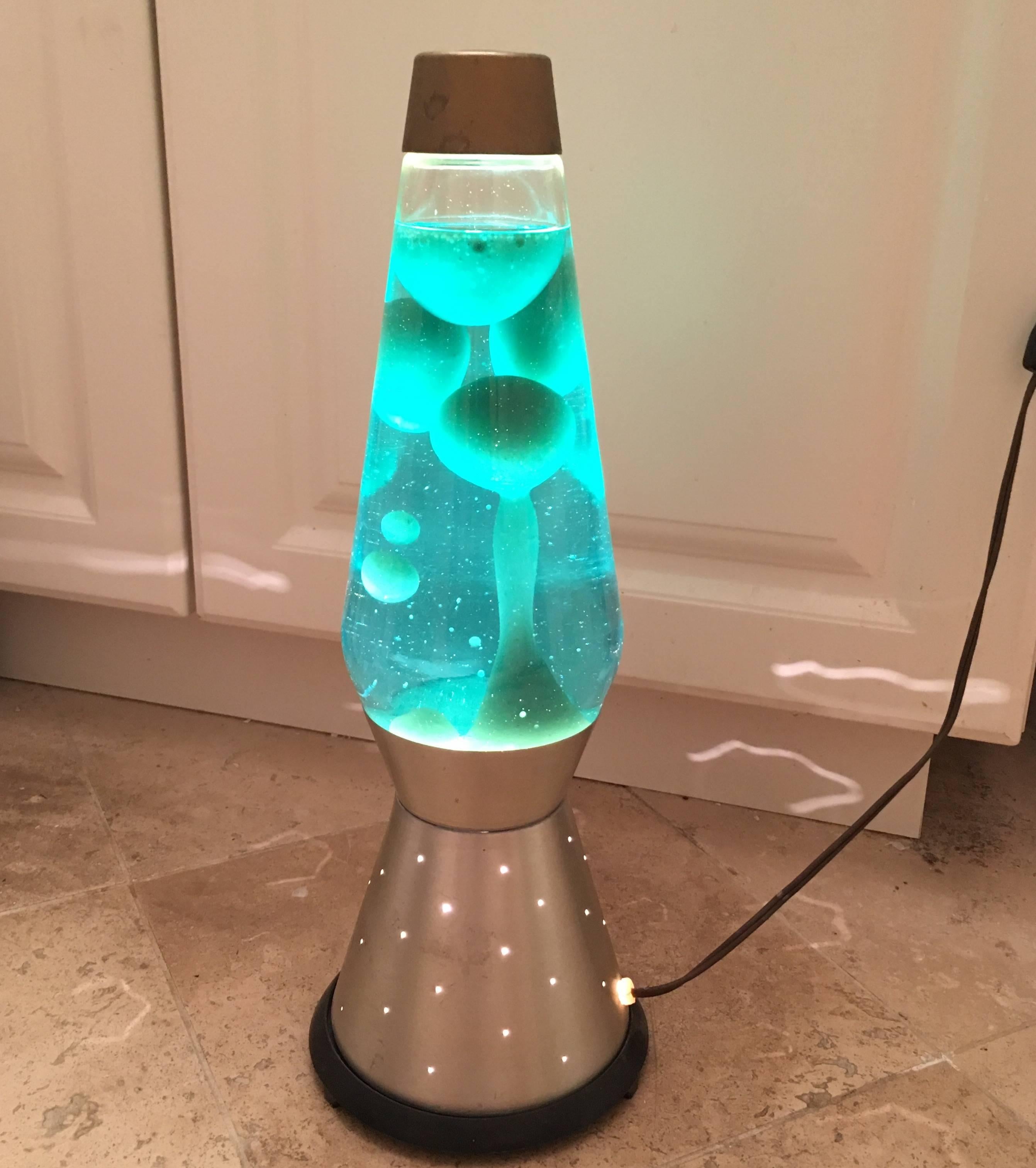 Terrific vintage Lava lamp by the Lava Symplex Company, 1970s. The lamp is comprised of blue liquid with white lava and Metal base. When lit the lava moves around and shadows are cast through the holes on the base. Truly a great mood light for your