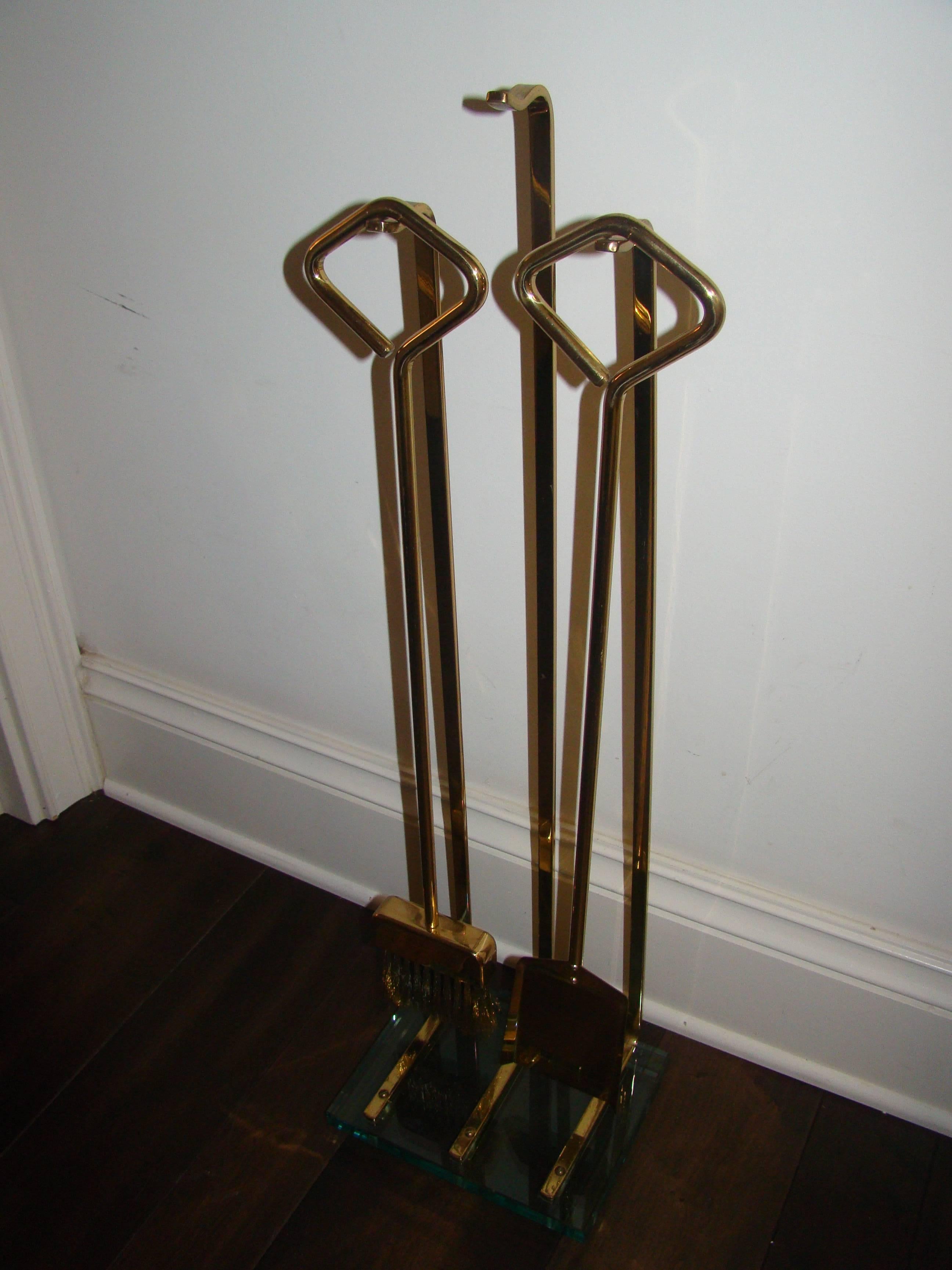 Great set of brass and glass fireplace tools in the manner of Fontana Arte. This stylish set is comprised of a green tinted glass base with three brass hangers. It has two tools, the poker is missing but one could easily be fabricated out of brass.