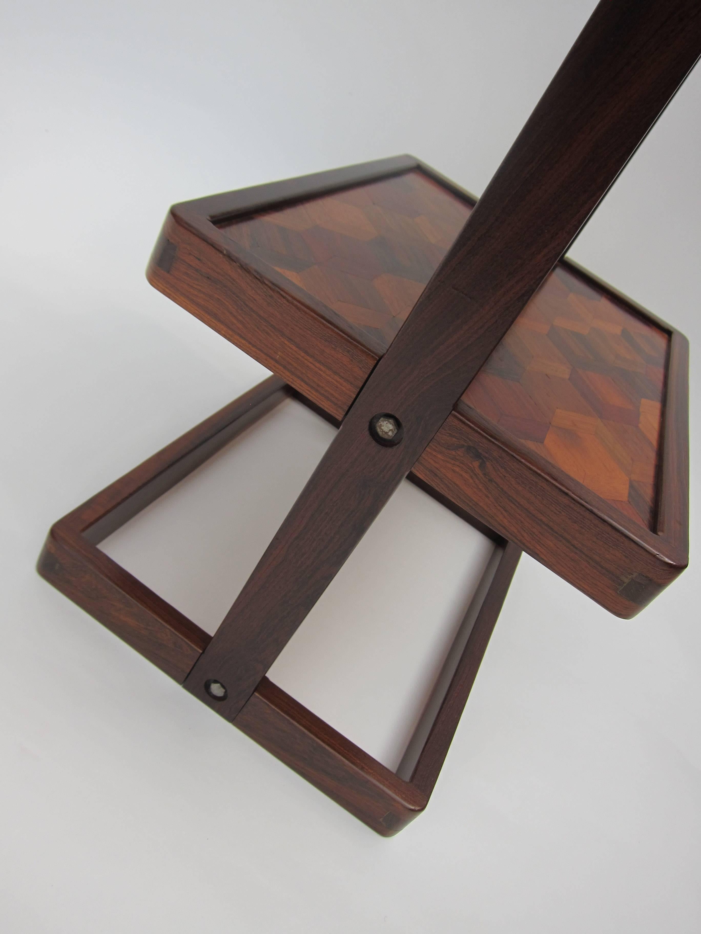 This is a beautifully crafted table by modernist master Don Shoemaker. The frame is solid tropical rosewood (cocobolo) and the 2 tiers show off the different tropical hardwoods in a parquetry pattern to wonderful effect.  
Don Shoemaker is one of