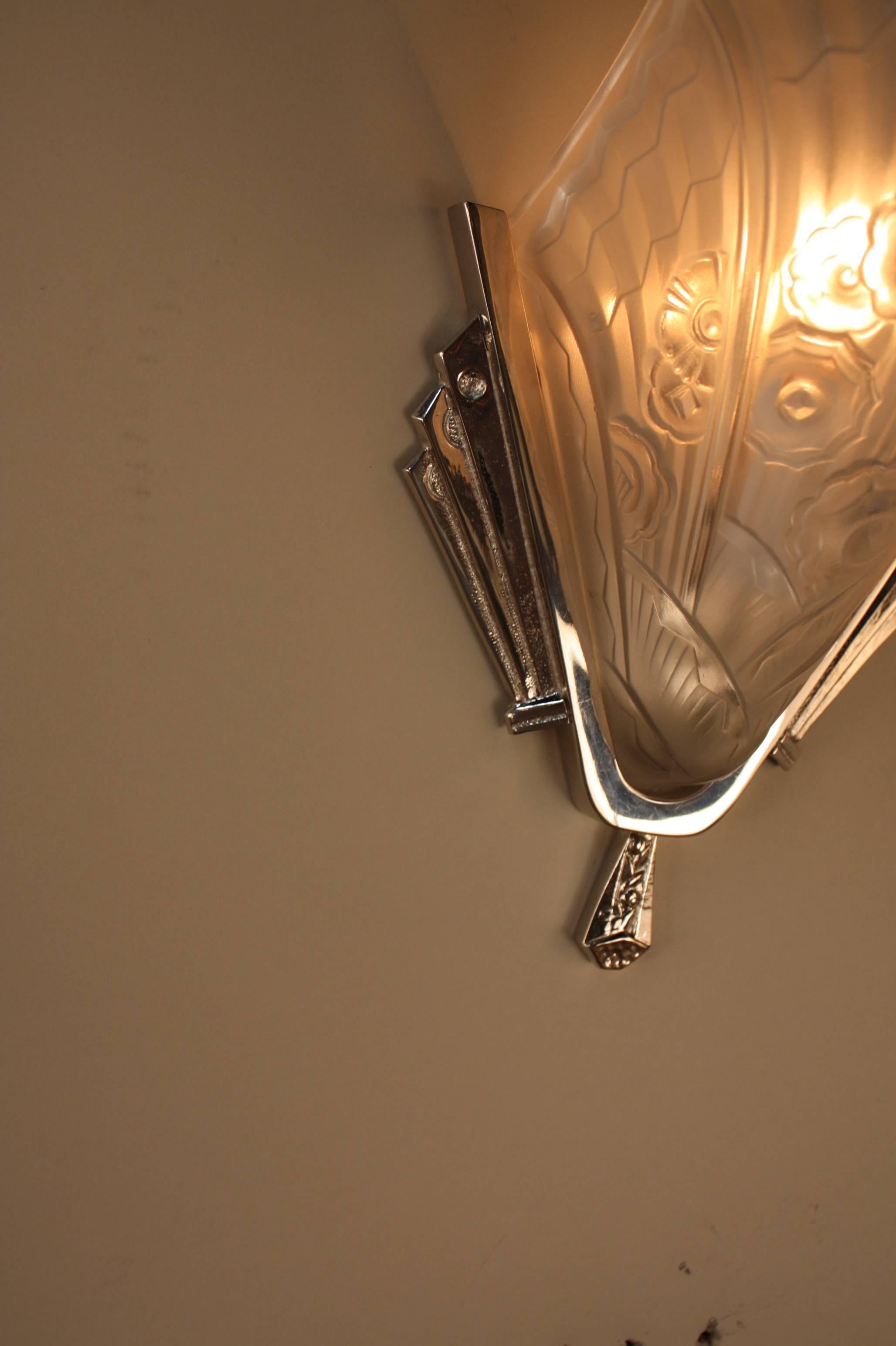 A beautiful pair of French Art Deco wall sconces with geometric flora design and polished nickel on bronze back plate.
 