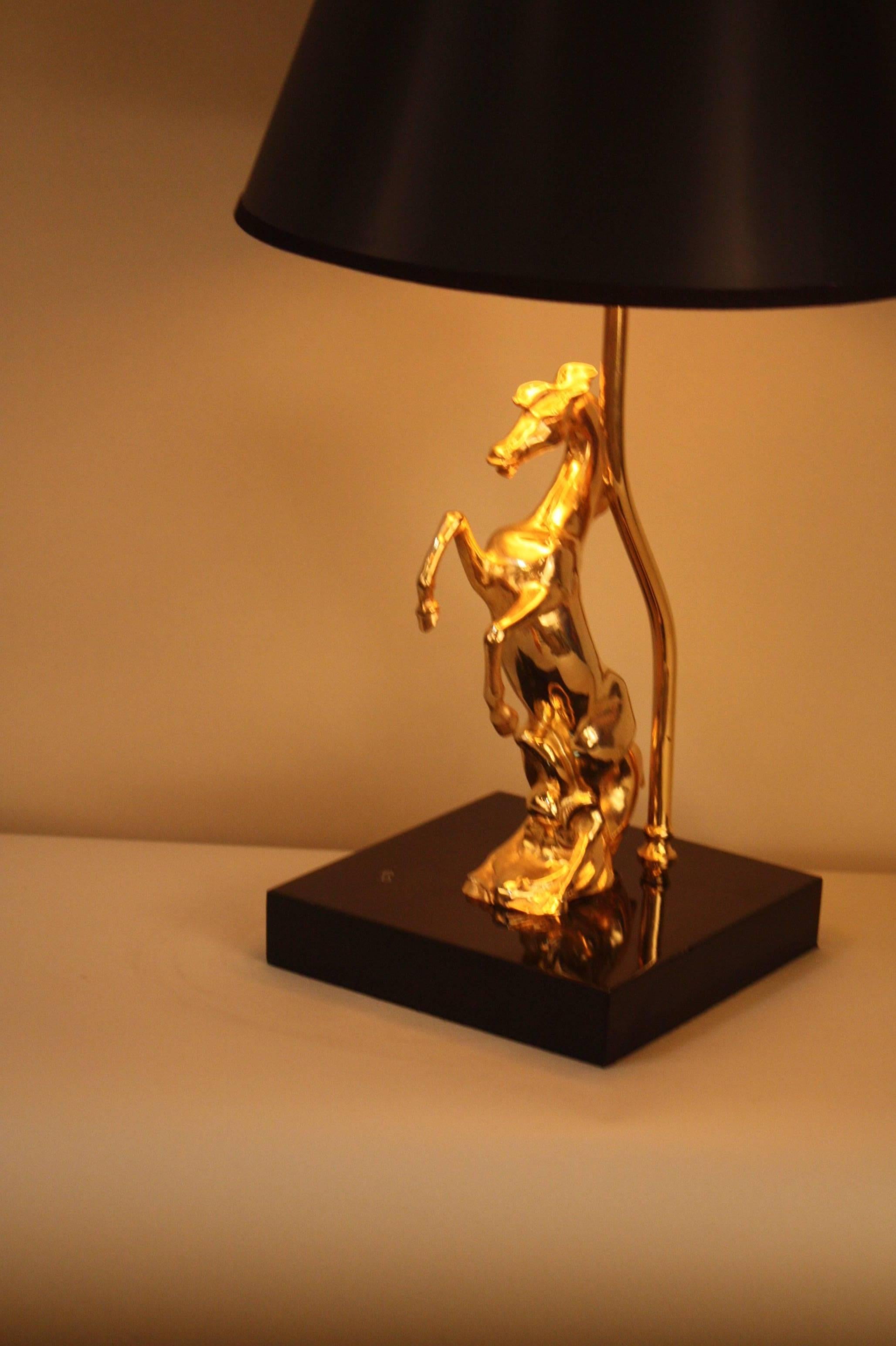 Elegant modern polished bronze horse sitting on black lacquer base table lamp. 
This lamp is fitted with black gold lining lampshade.