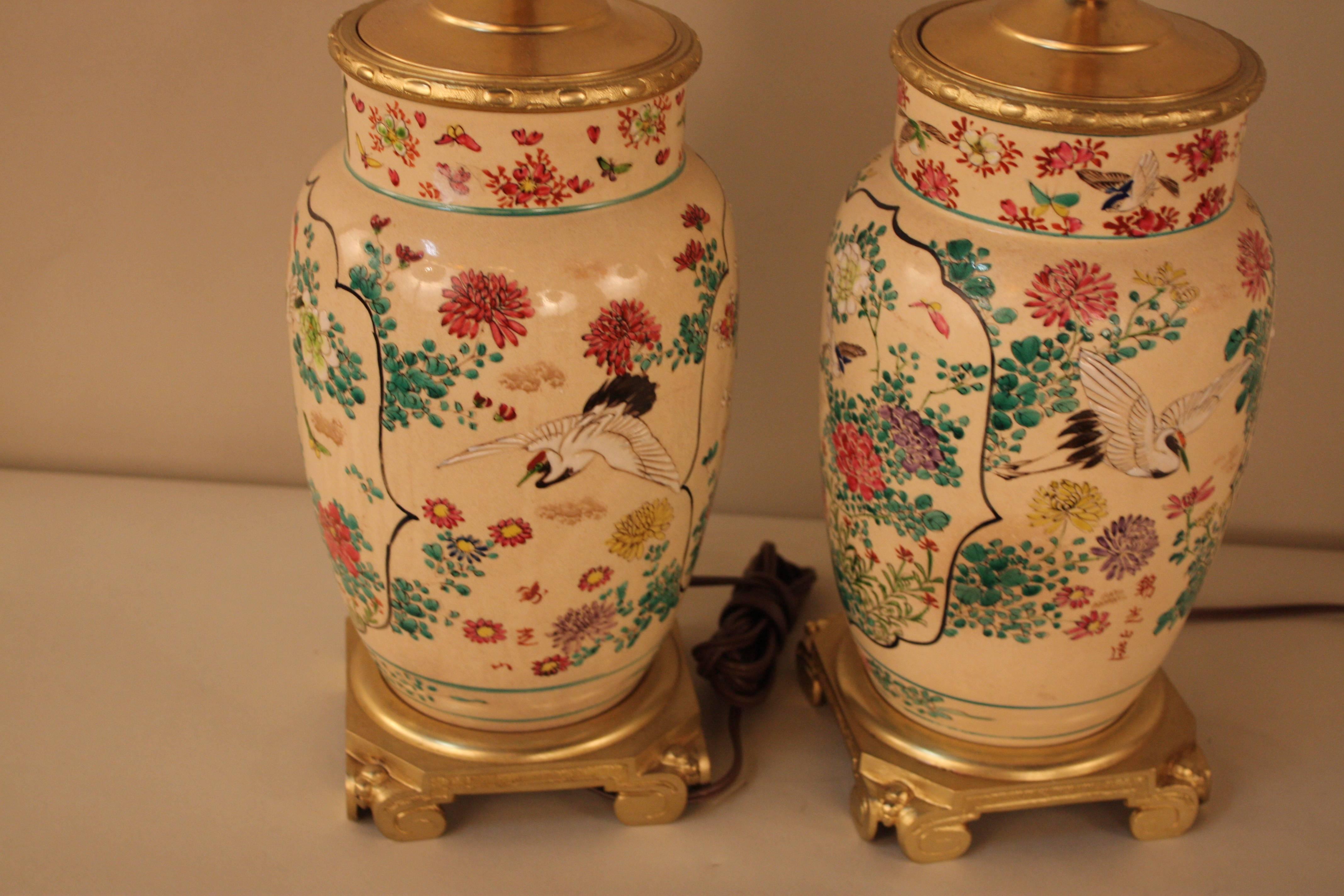 A beautiful hand-painted pair of porcelain modified and electrified oil lamps influenced by oriental art with Classic bronze mounting makes these pieces absolutely stunning.