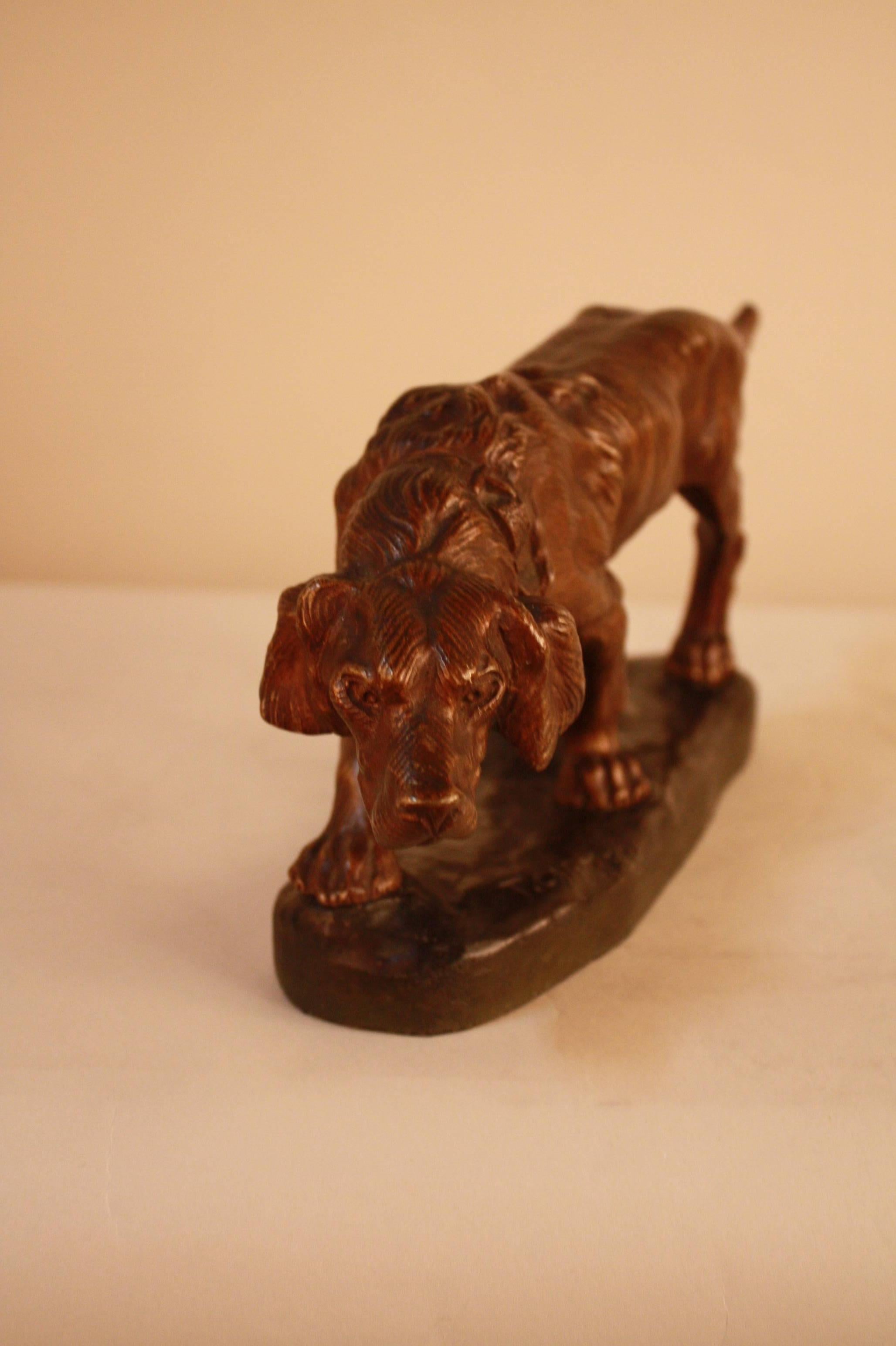 A sculpture figure of a hunting dog in brown and green patina by Thomas Francois Cartier (French, 1879 to 1943).