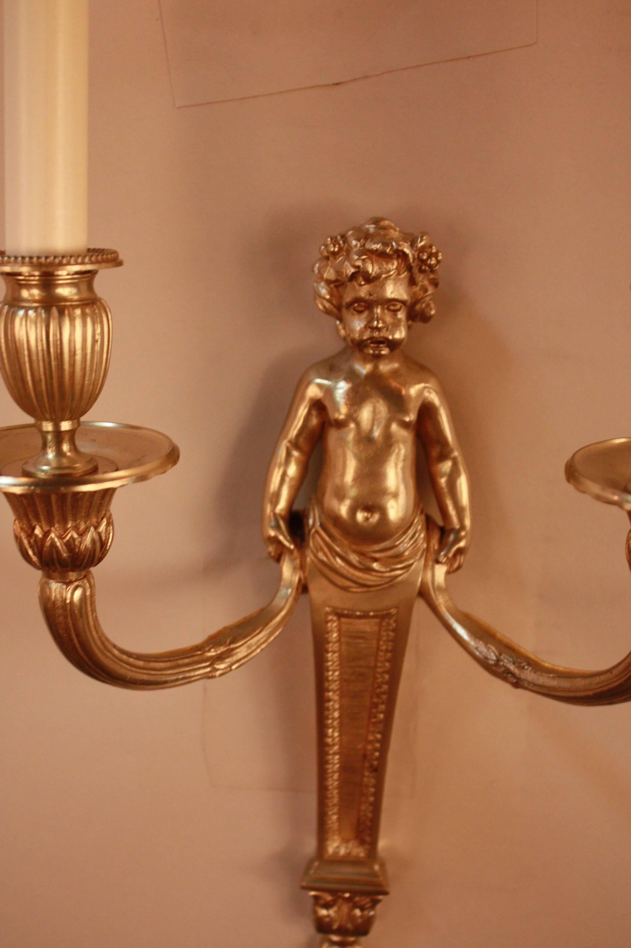 Elegant double-arm bronze wall sconces with putto holding the arms.