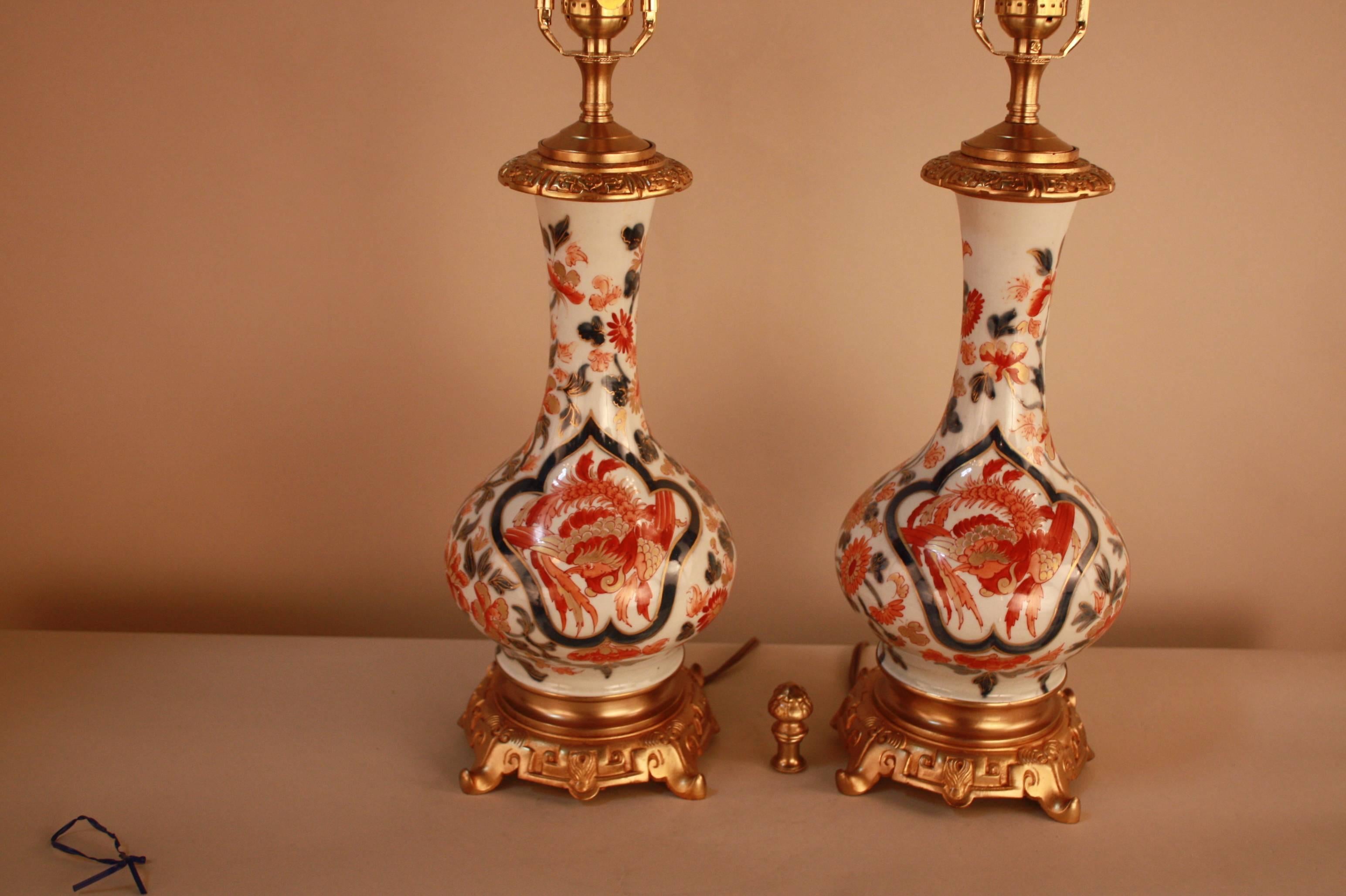 A beautiful pair of 19th century hand-painted porcelain lamps, depicting a dragon on one side and a bird on the reverse side. Base made of bronze. 

Originally oil lamps, these have been modified with electric wiring and fitted with new box pleat