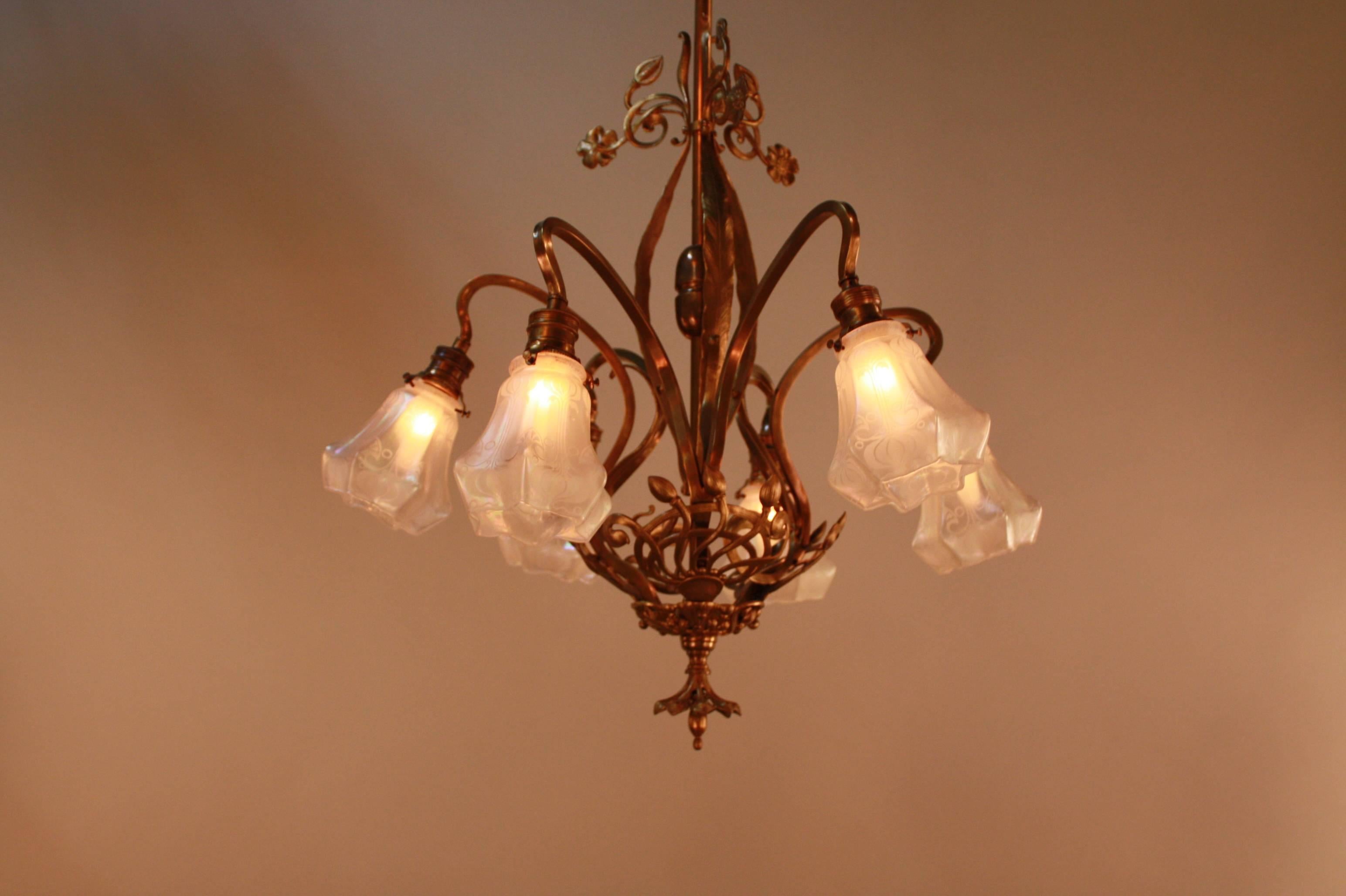 A fabulous Art Nouveau chandelier. An elegant bronze with organic and flora design characteristic of the Art Nouveau period. Features acid etched indecent glass shades.