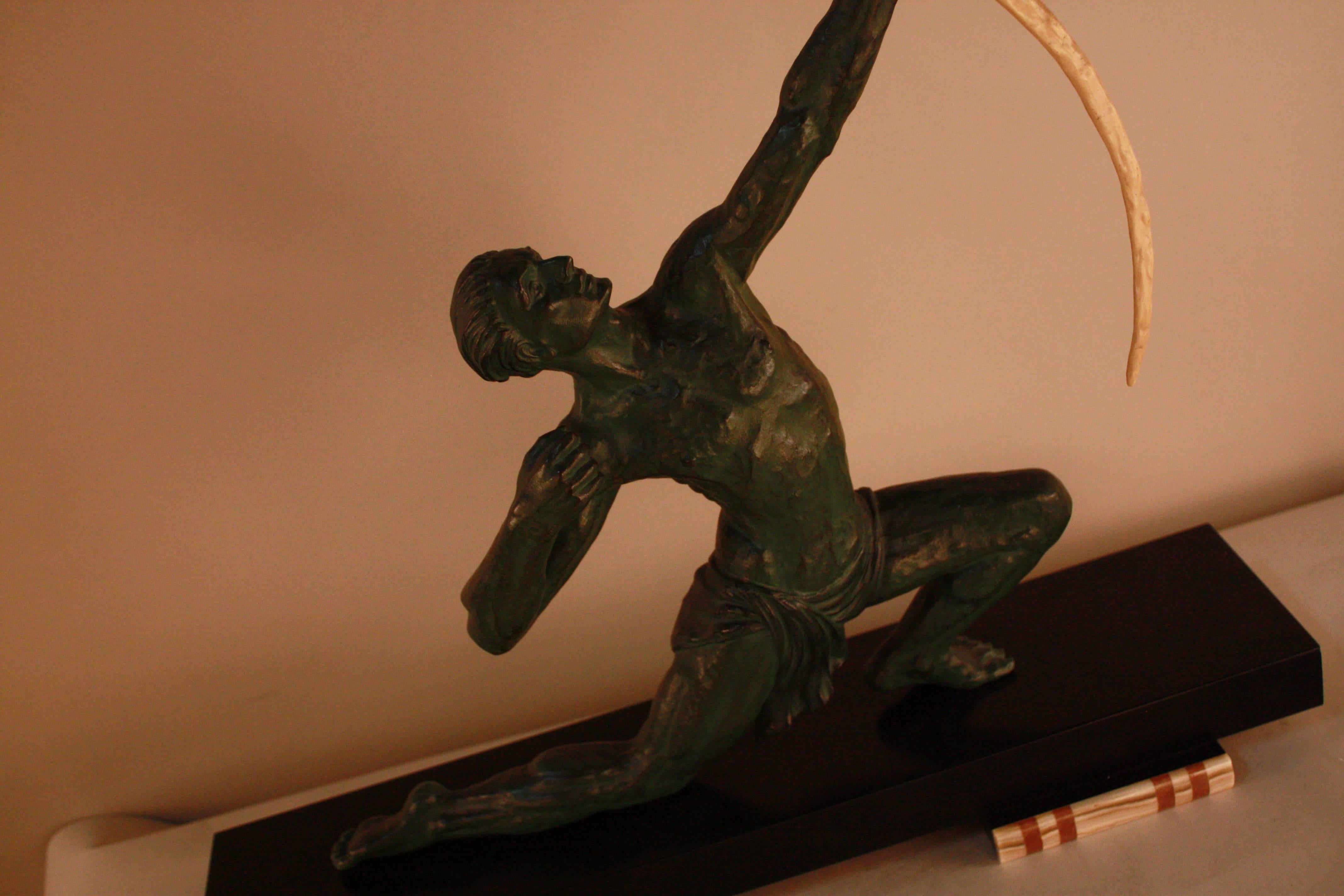 A superb Art Deco sculpture. Green patina spelter semi-nude male archer over a black marble base.