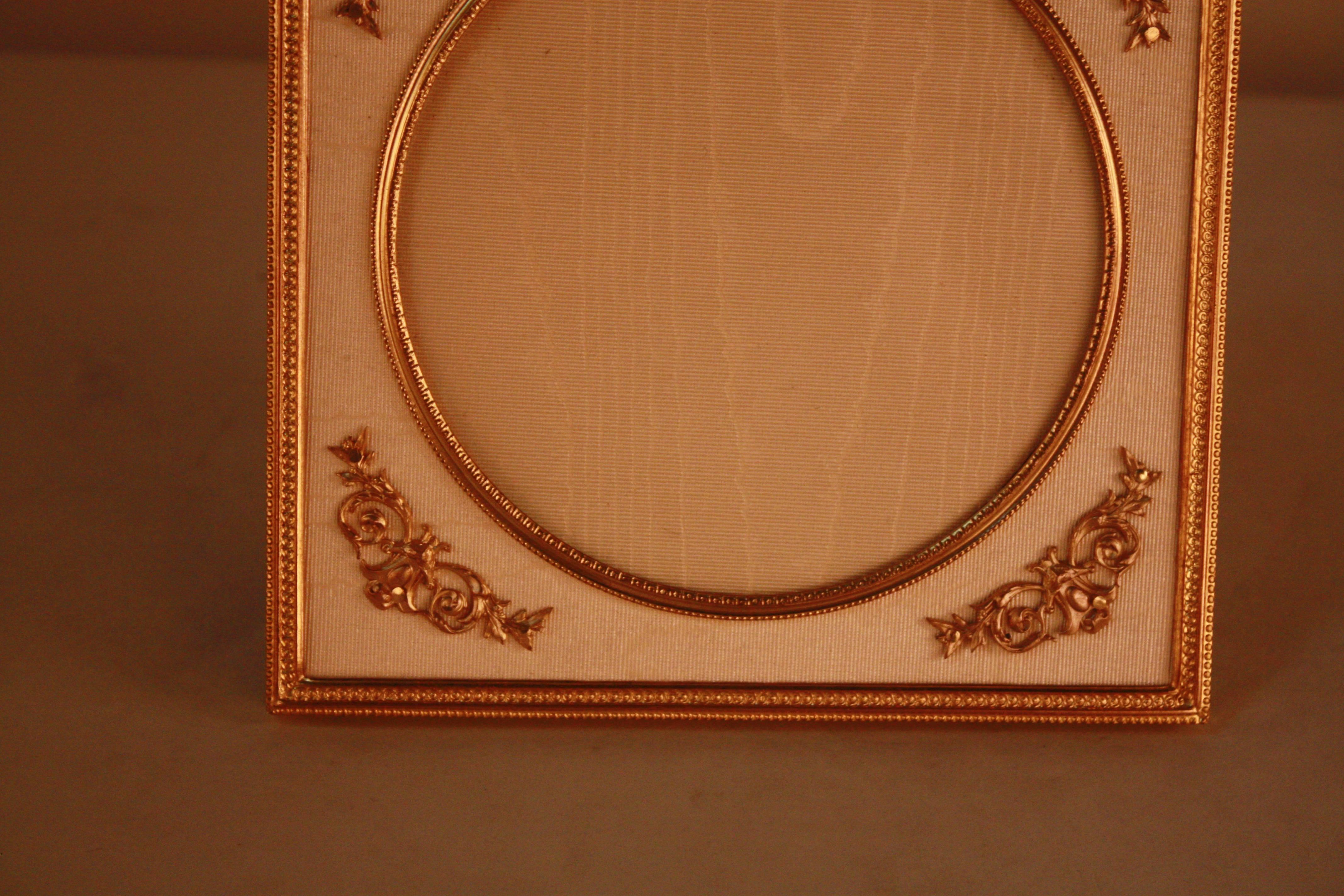 A rare 19th century French Empire gilded bronze picture frame, featuring a bow at the top. A playful piece with a warm color. 
Circular space for an image, with a 4.5