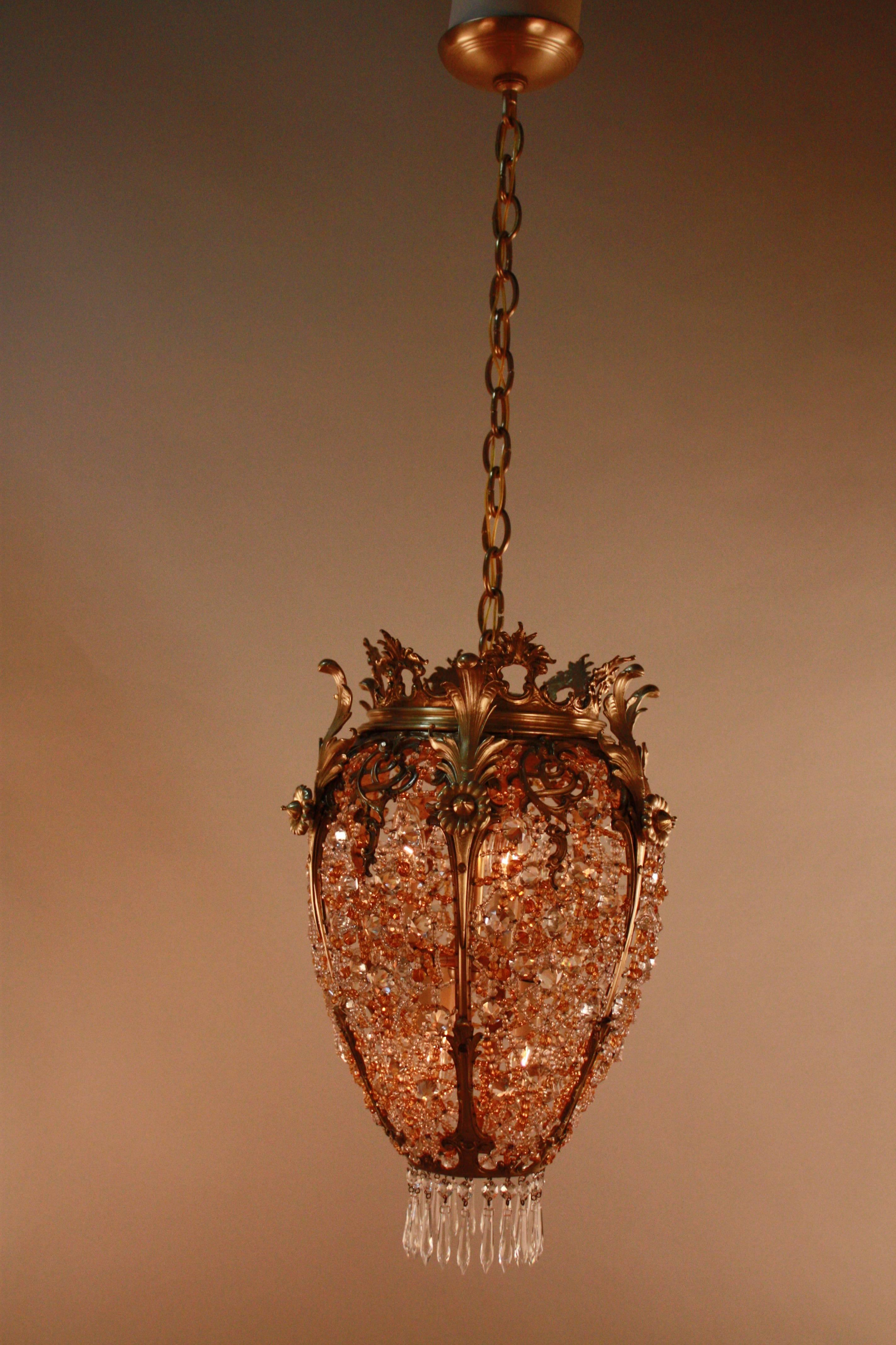 This jewel chandelier, made in France during the 1930's, is handmade with clear, gold and amber colored crystals with a bronze frame. When installed, this piece has a minimum height of 25