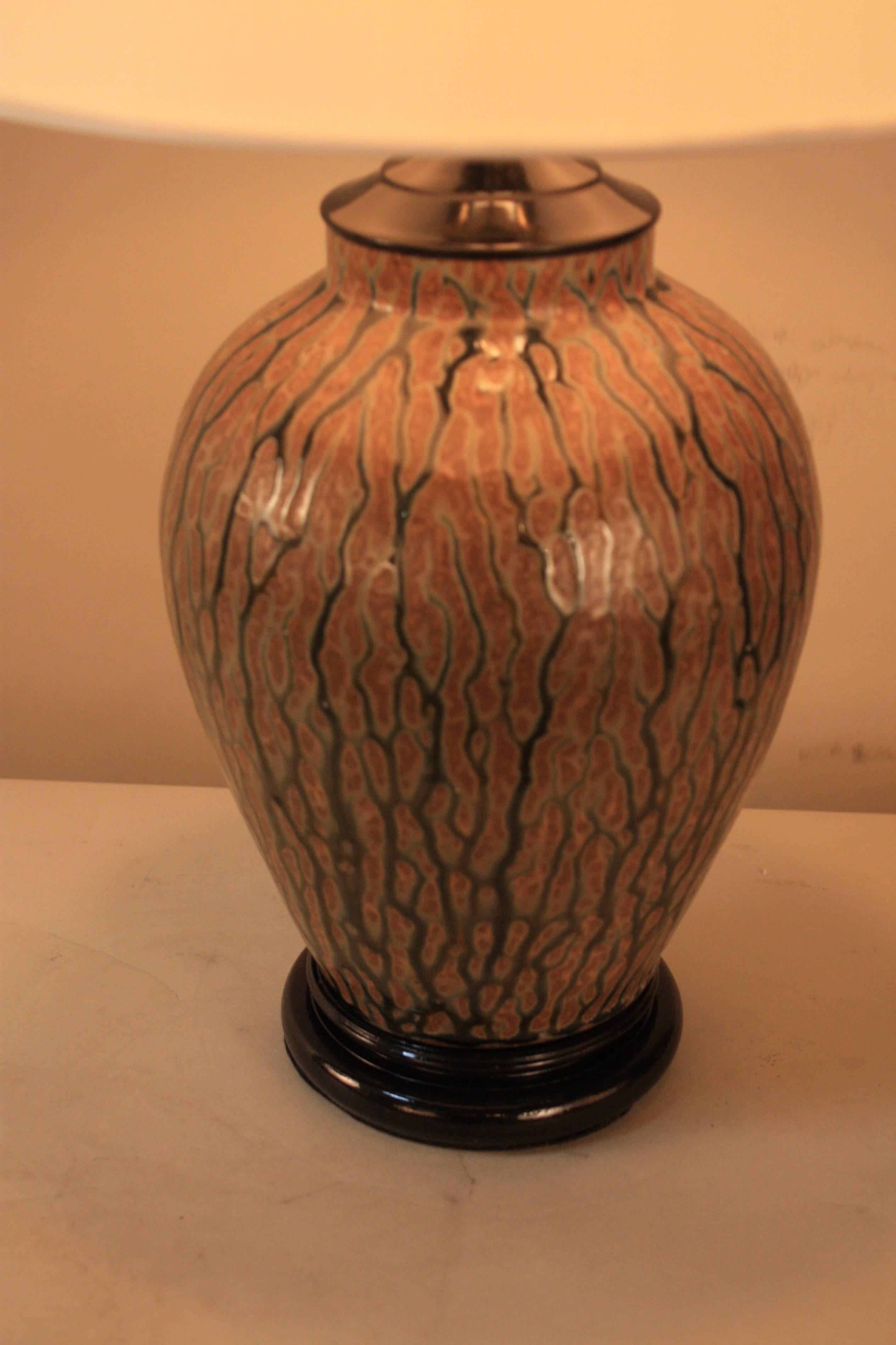 An organic-inspired decorative vase that has been customized into a table lamp and fitted with a silk lampshade. 