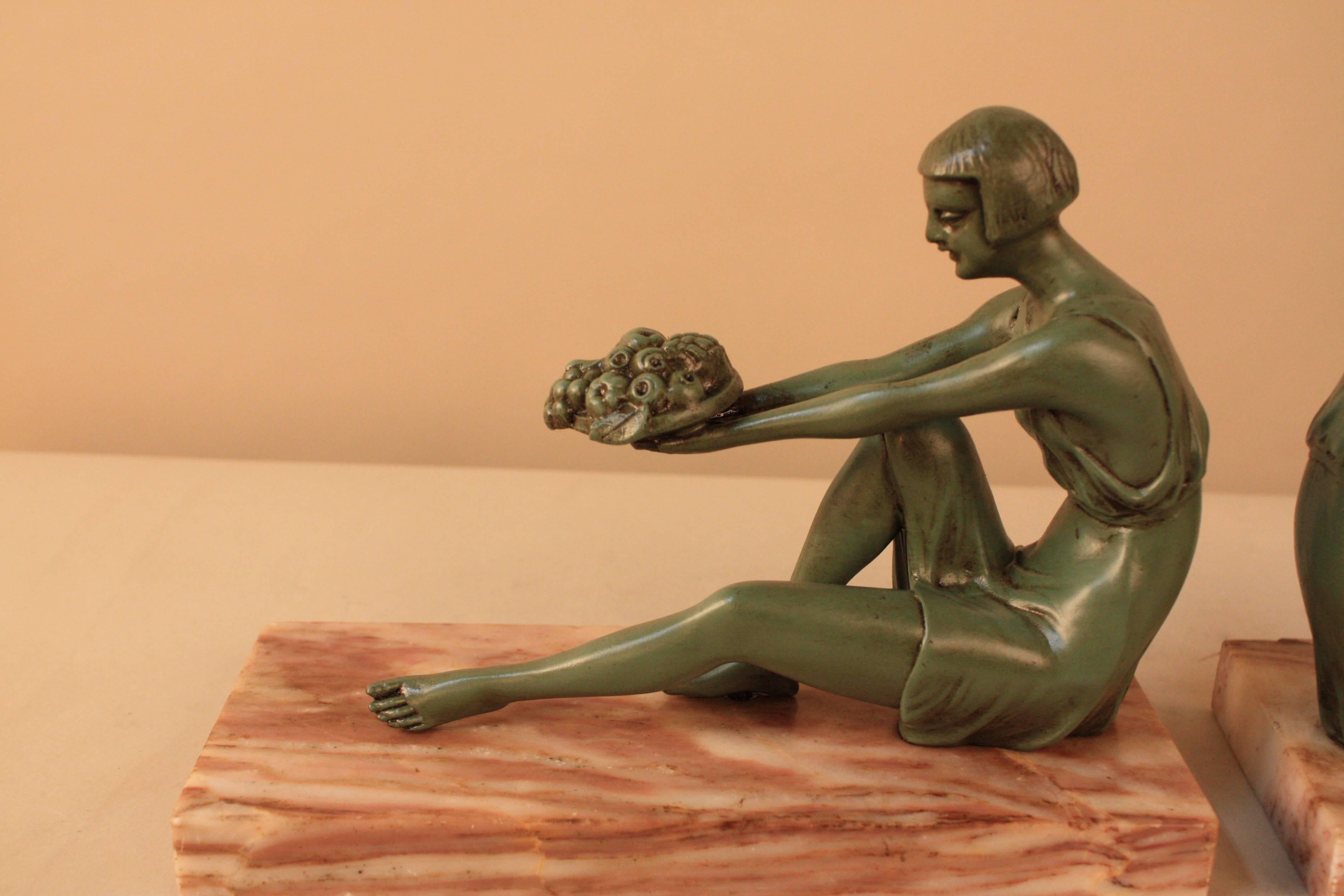 Pair of Art Deco bookends with girl sitting offering fruit, cold green paint patina sitting on red and beige marble.
Measurement of the width is for both.
                    