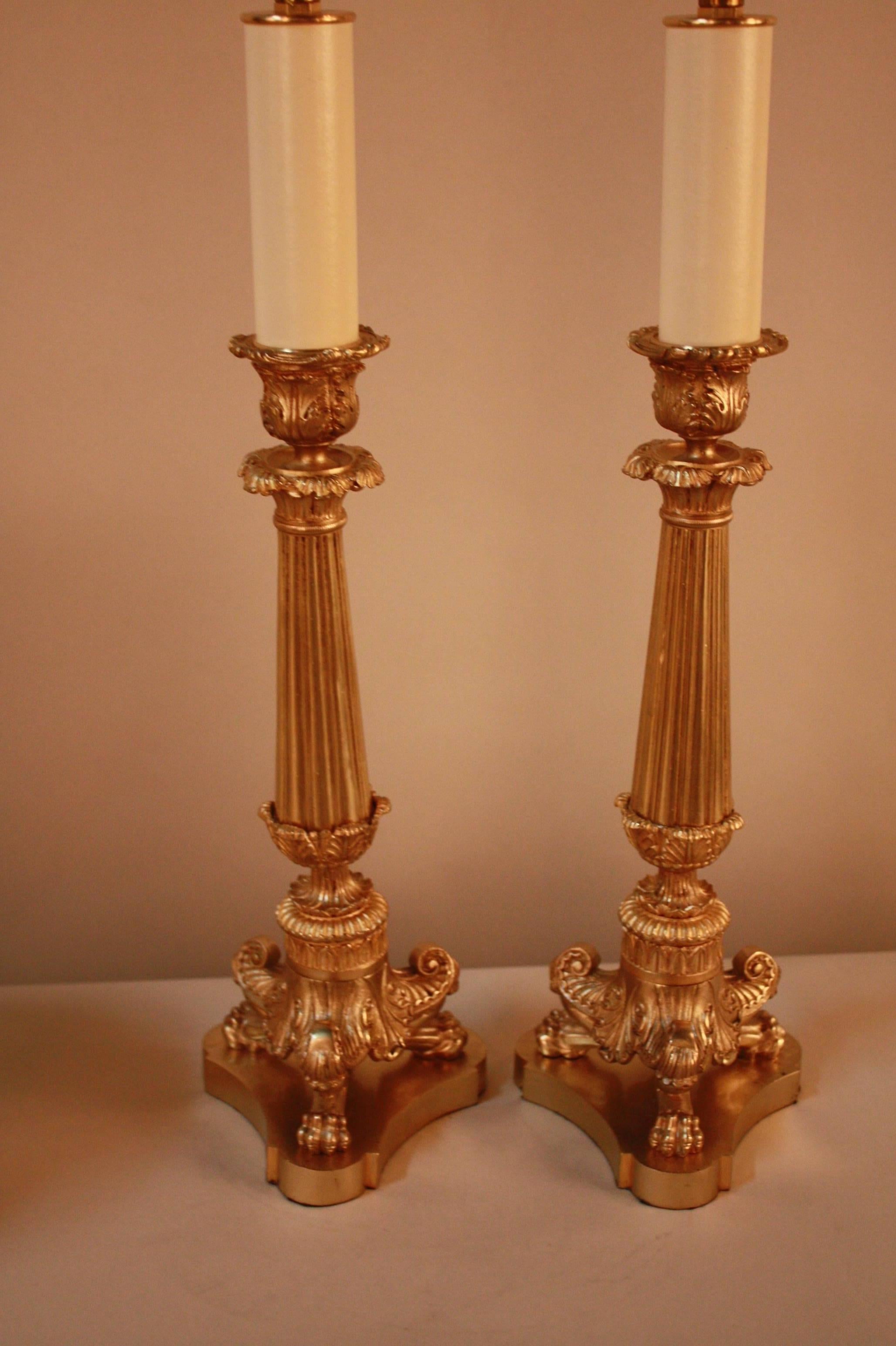 An impressive pair of Classic Empire style candlestick lamps supported on Bacchus and lions paw tri-form feet.