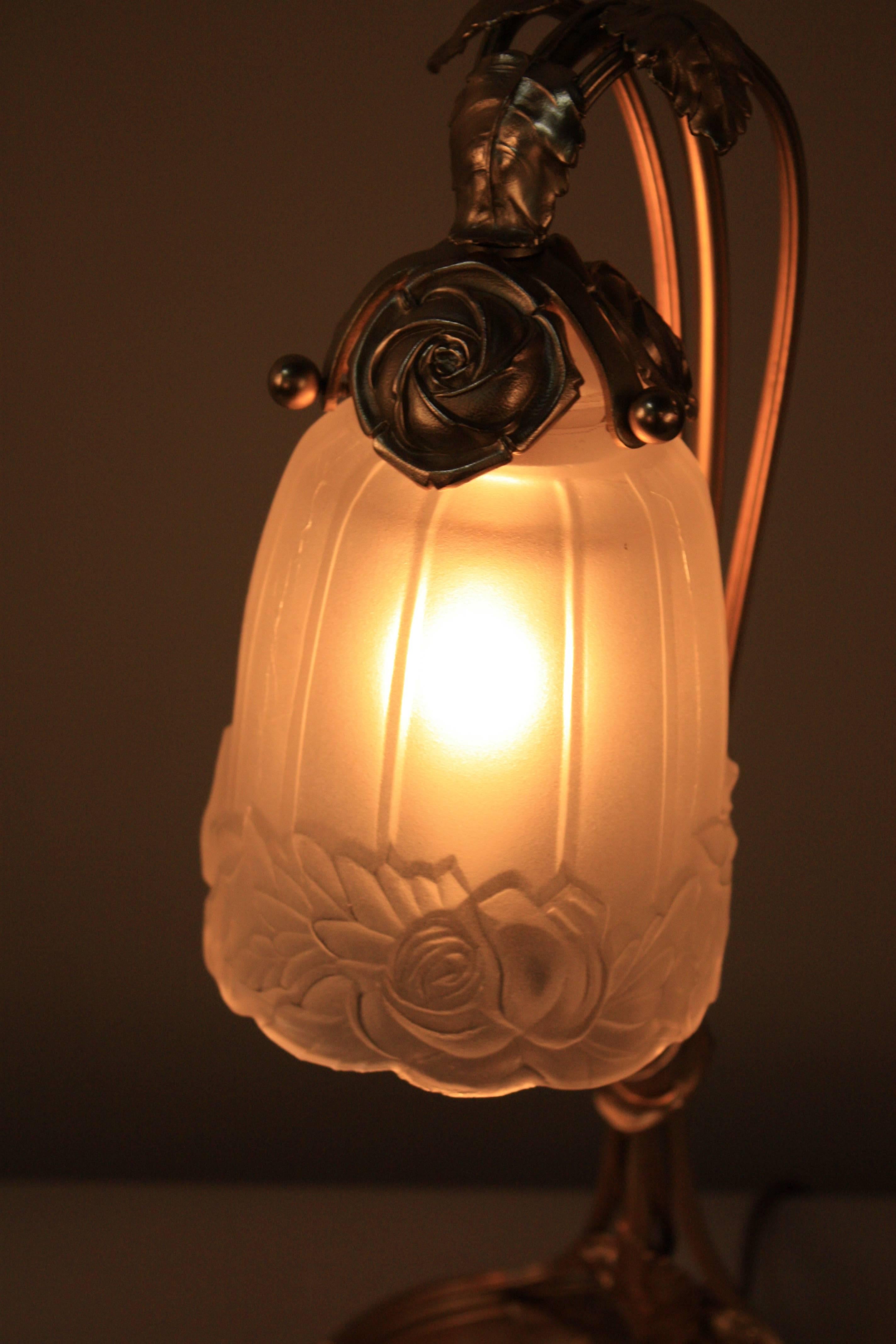A twisted arm with leaves and flora design table lamp sitting on onyx base and holing a floral design glass shade.