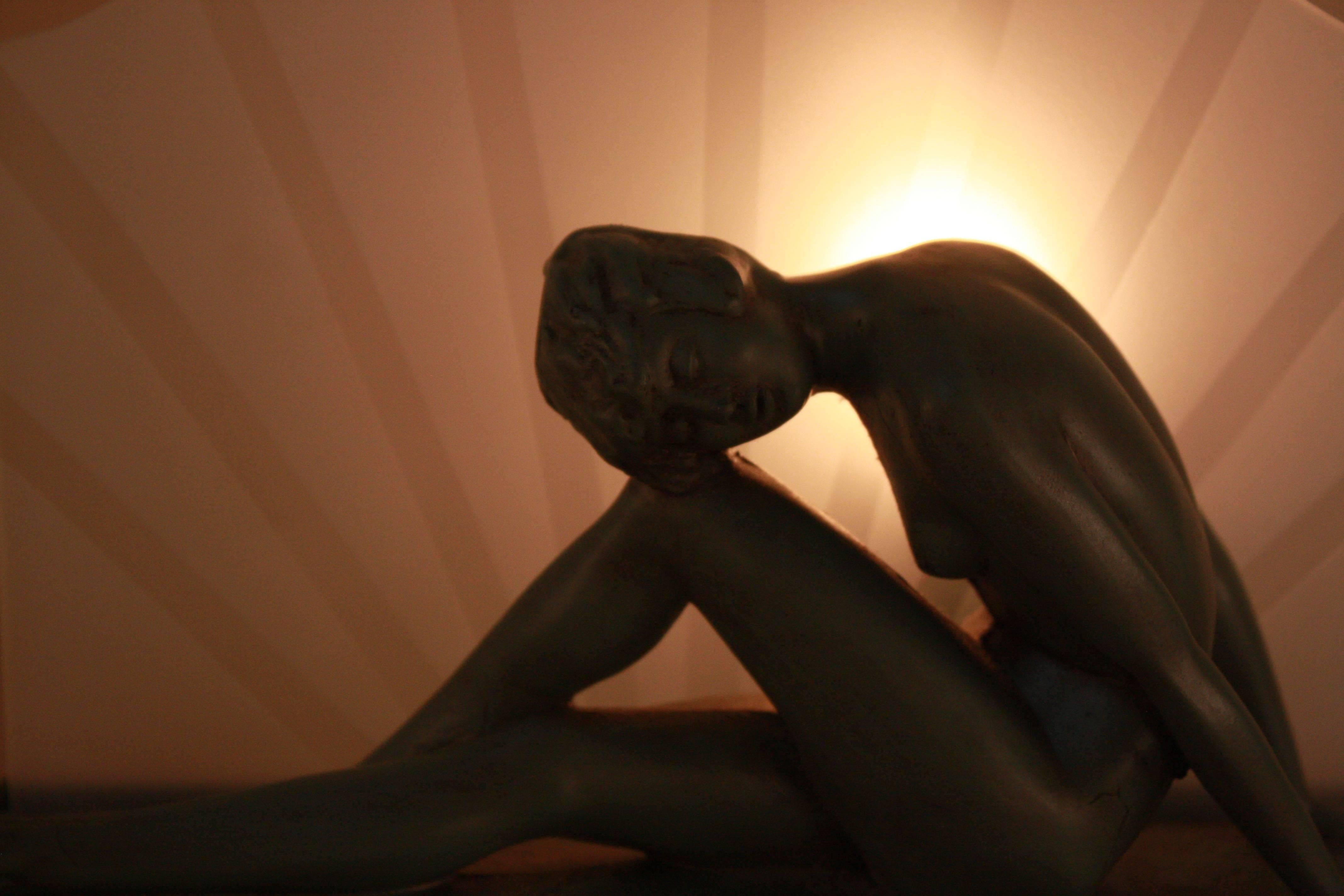 Made during 1930s, nude sitting woman in front of sun blast glass table lamp.
