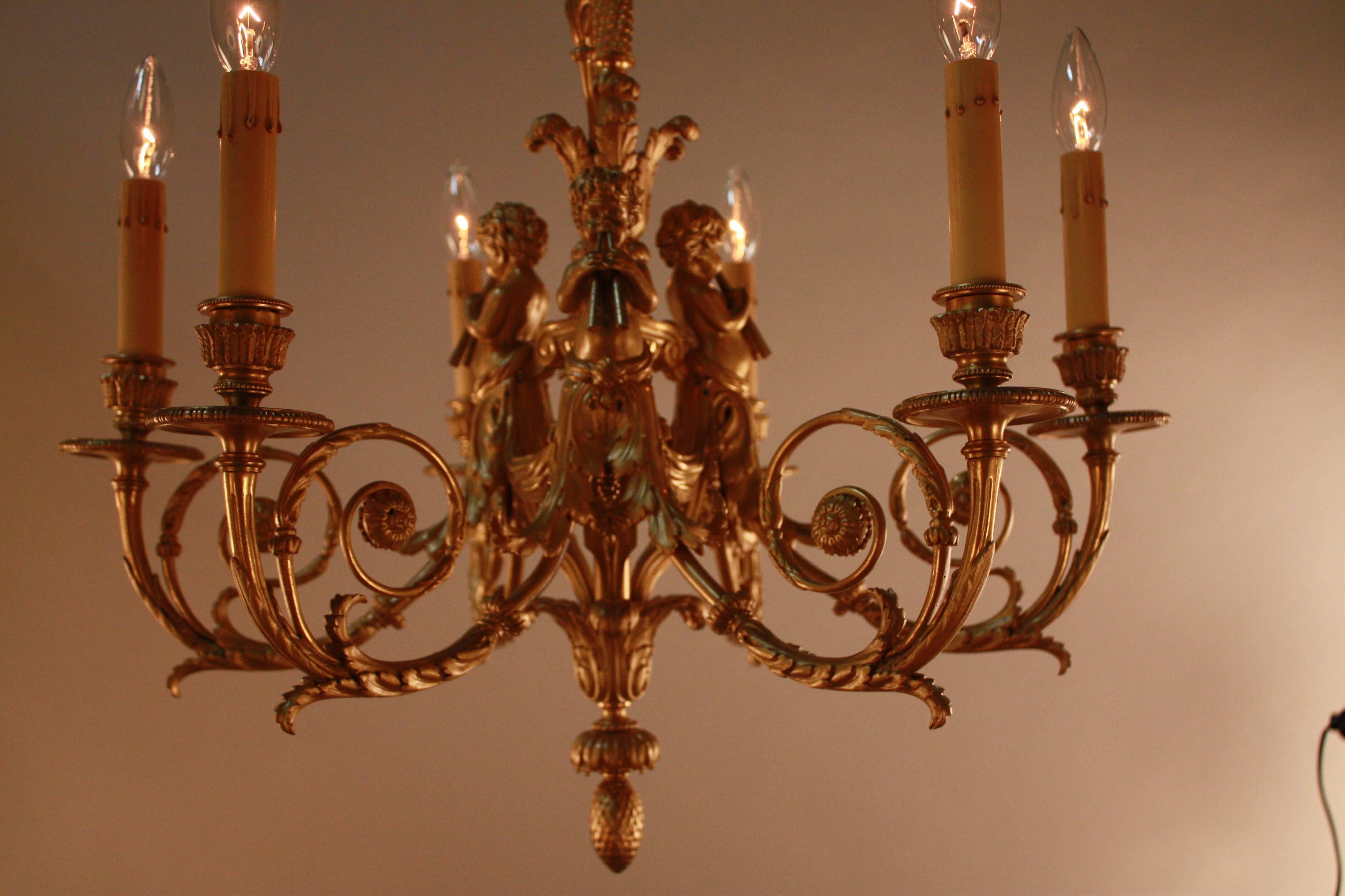 Early 20th century six-light electrified ormolu chandelier with figures of seated putti, centred by an acanthus-cast pendant.