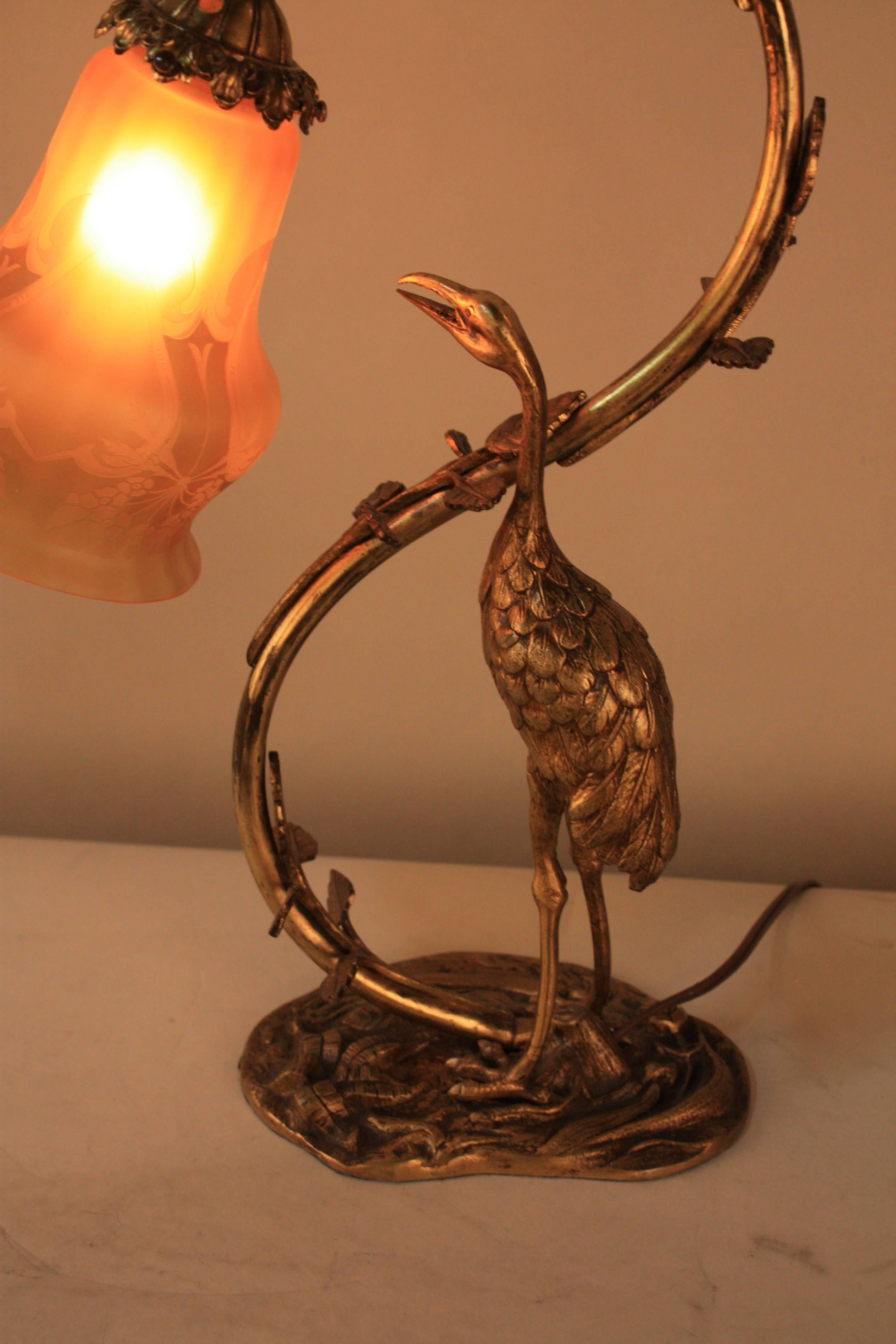 Masterfully crafted in France during the early 1900s, this beautiful bronze table lamp features an Classic organically-inspired Art Nouveau design. A wonderful sculptural stork rendering serves as this gorgeous table lamp's ornate centerpiece. A
