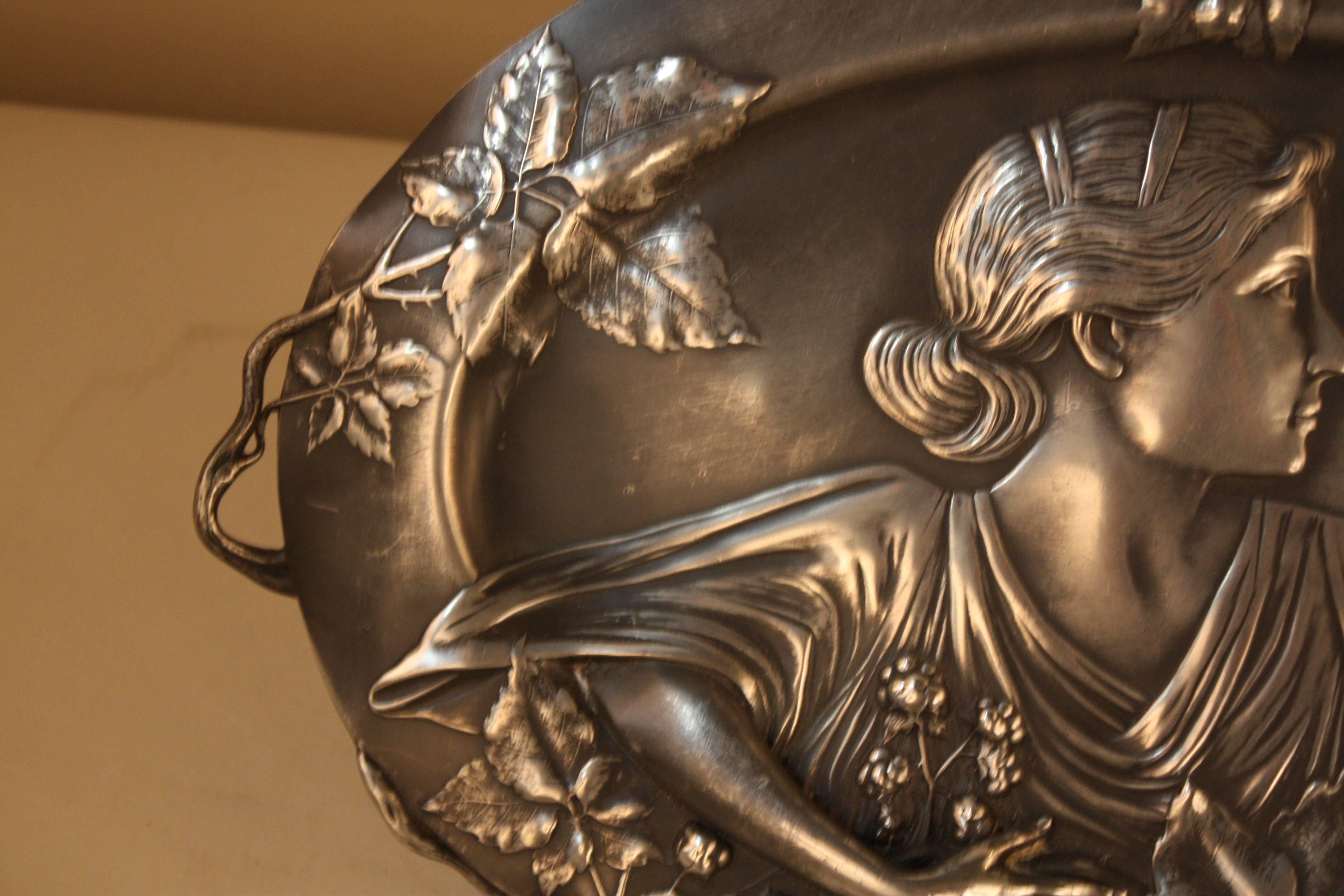Silver on pewter French Art Nouveau wall plaque or tray depicting a woman holding flower.

 