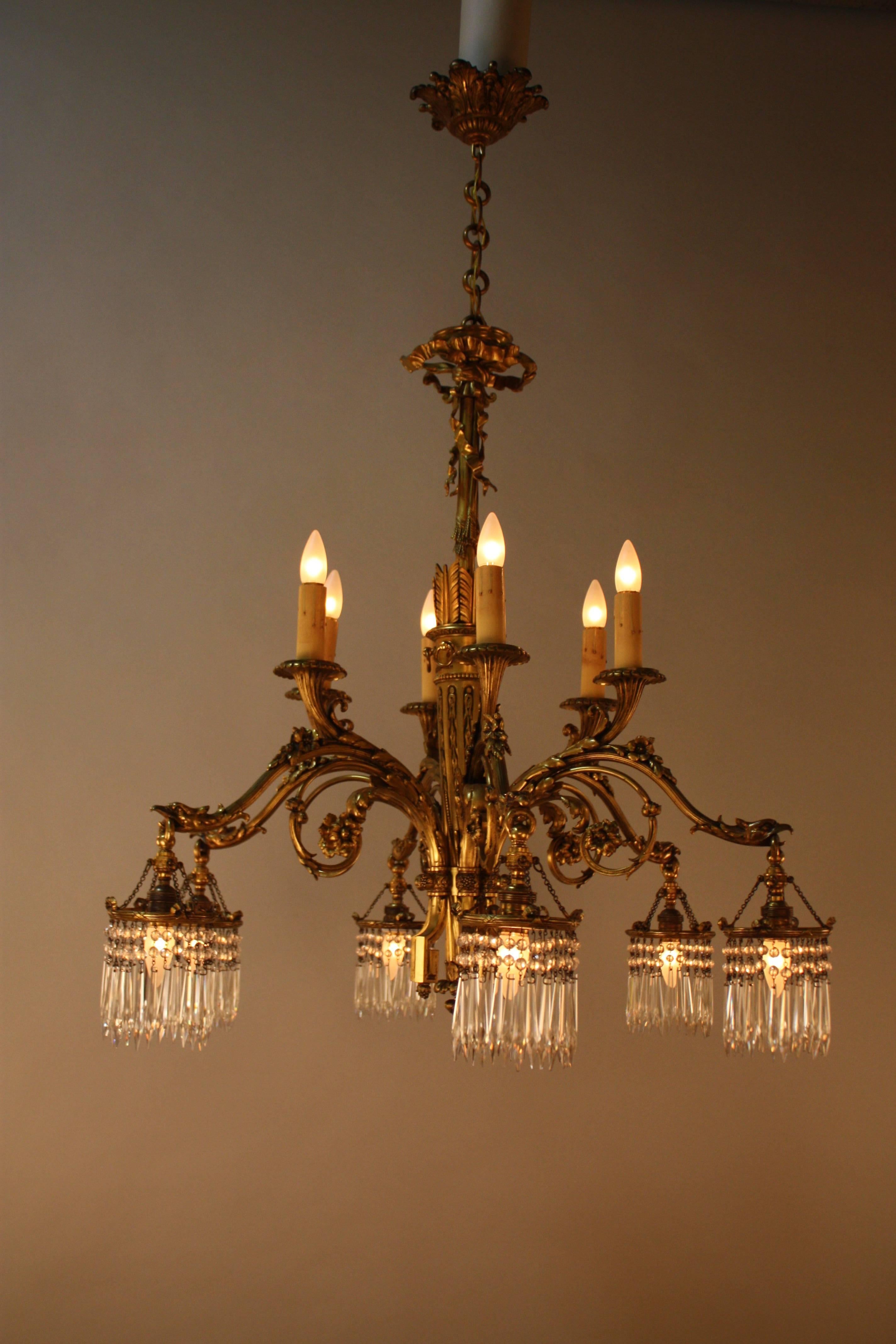 A superb Empire style bronze chandelier. French 1930s elegant design high quality twelve light chandelier with six candle style light and six down lighting with crystal surrounding the light bulbs.