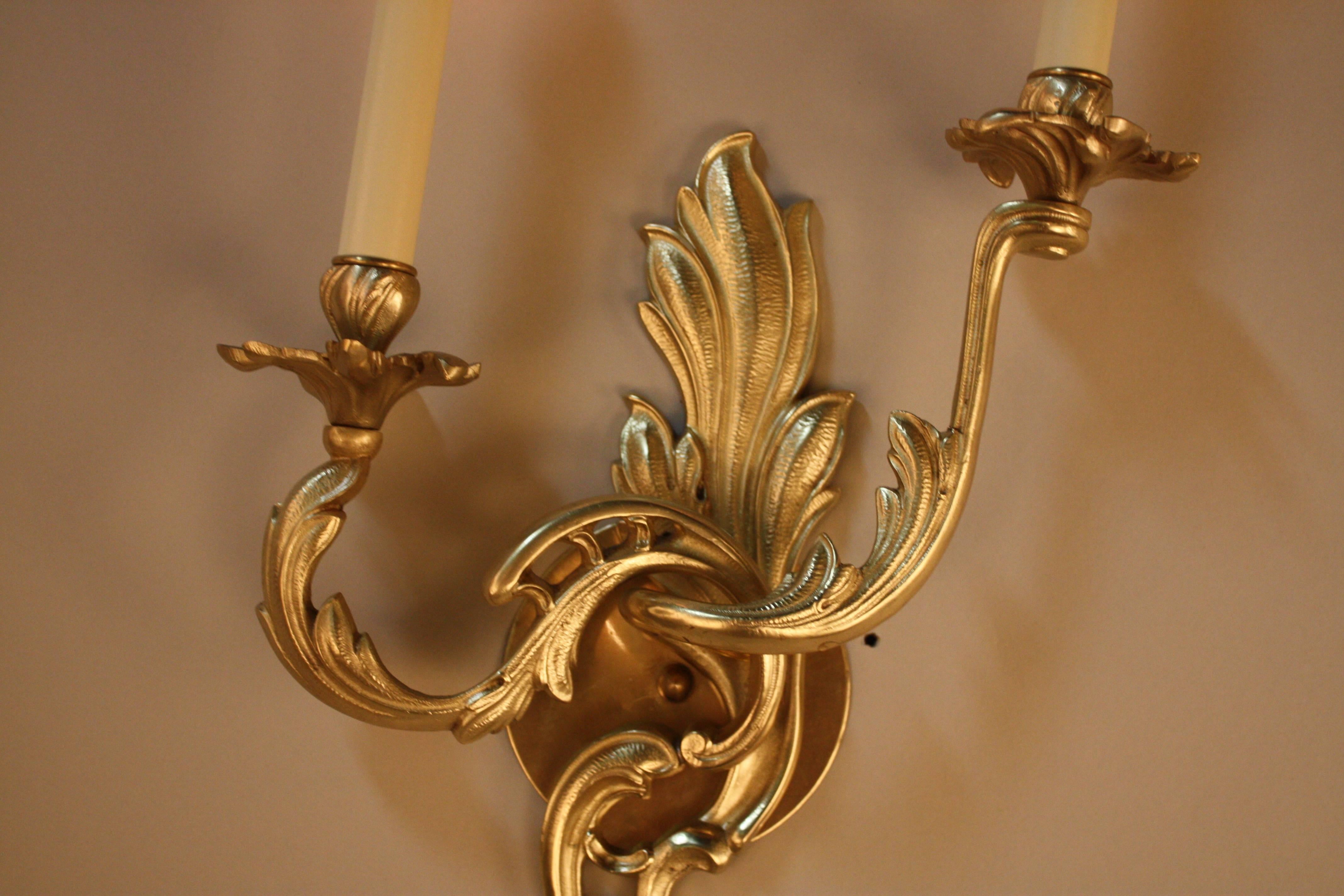 An elegant pair of double arm wall sconces. Made in France during the 1930s, this pair of sconces features beautiful bronze in an organically-inspired design; a classic example of Art Nouveau.