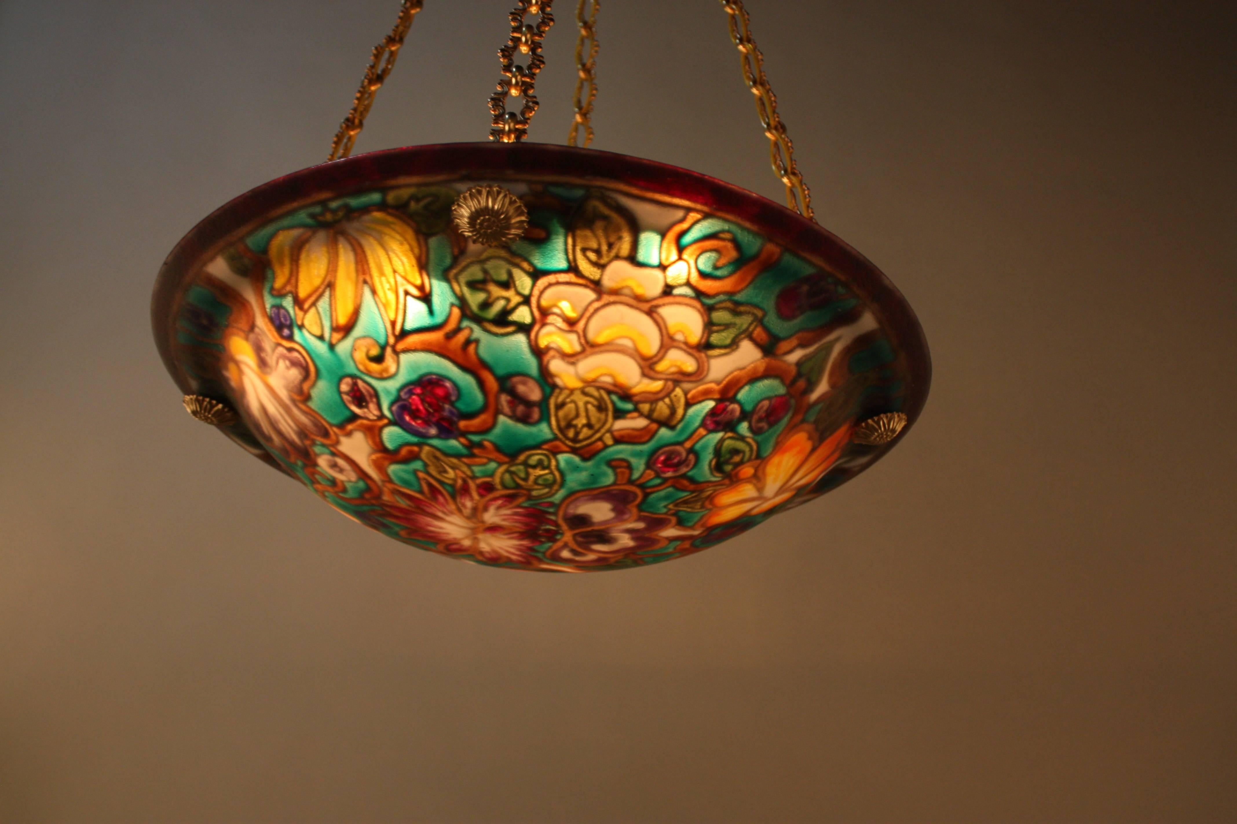 Fantastic reverse painted glass chandelier. Masterfully painted in the same style of late 19th or early 20th century that the thickness of glazed paint reflects the shape and color of the flowers through glass.
Bronze chain and canopy.
Measures: