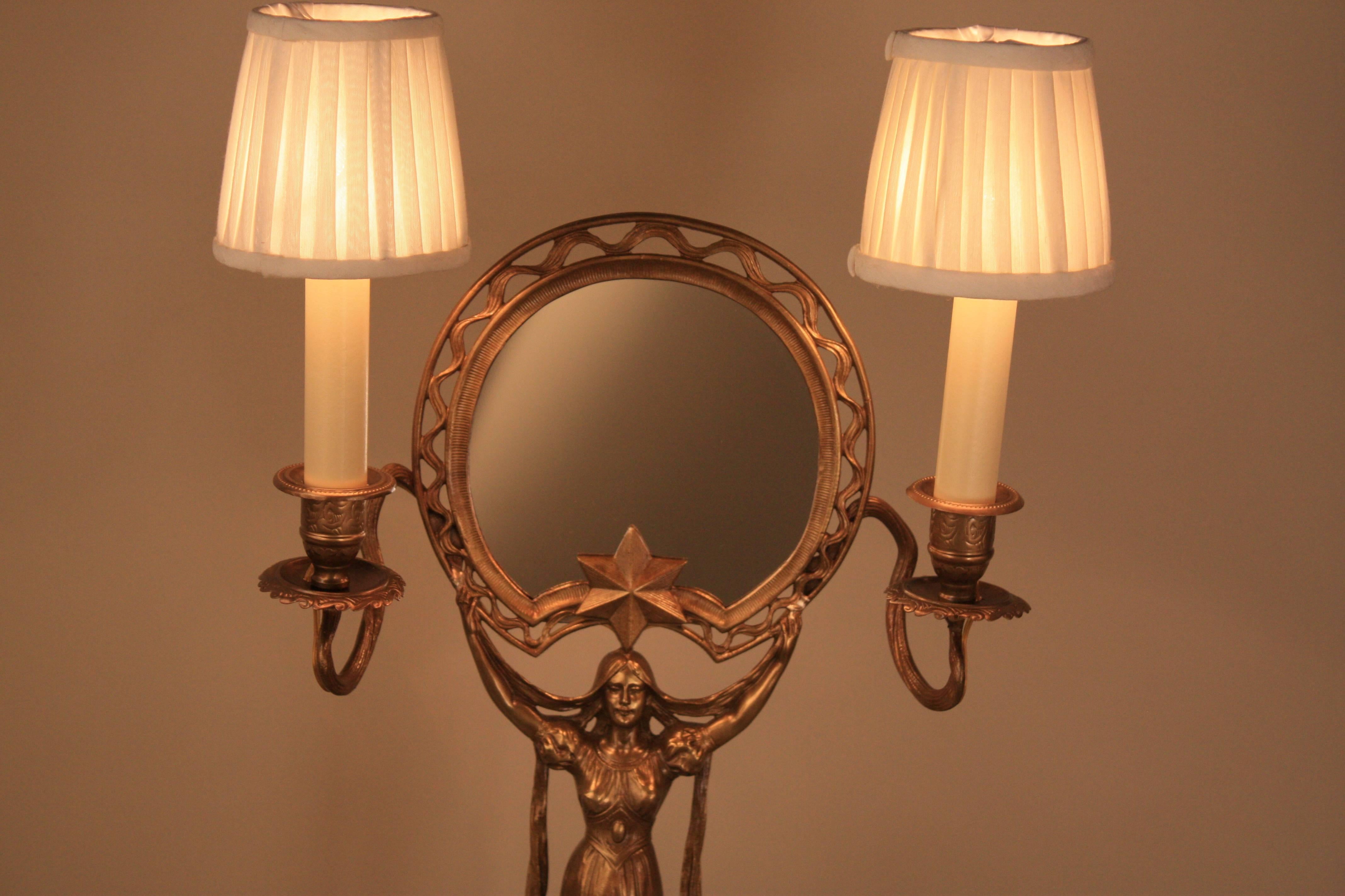 An Art Nouveau mirror in organic design, woman holding the mirror with two electrified candleholders.
