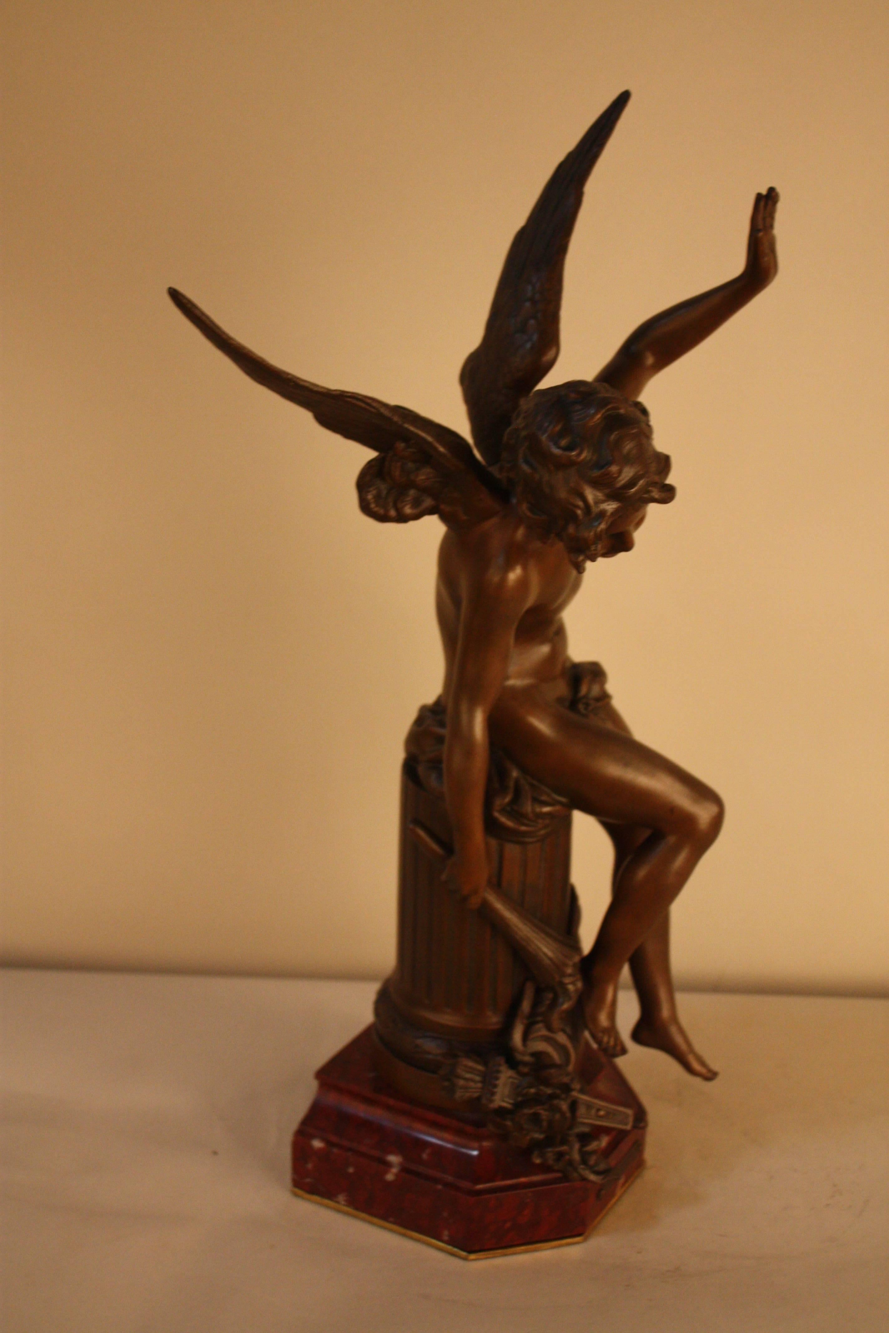 A bronze sculpture cupid boy or angel carrying a torch setting on column with rouge marble base.