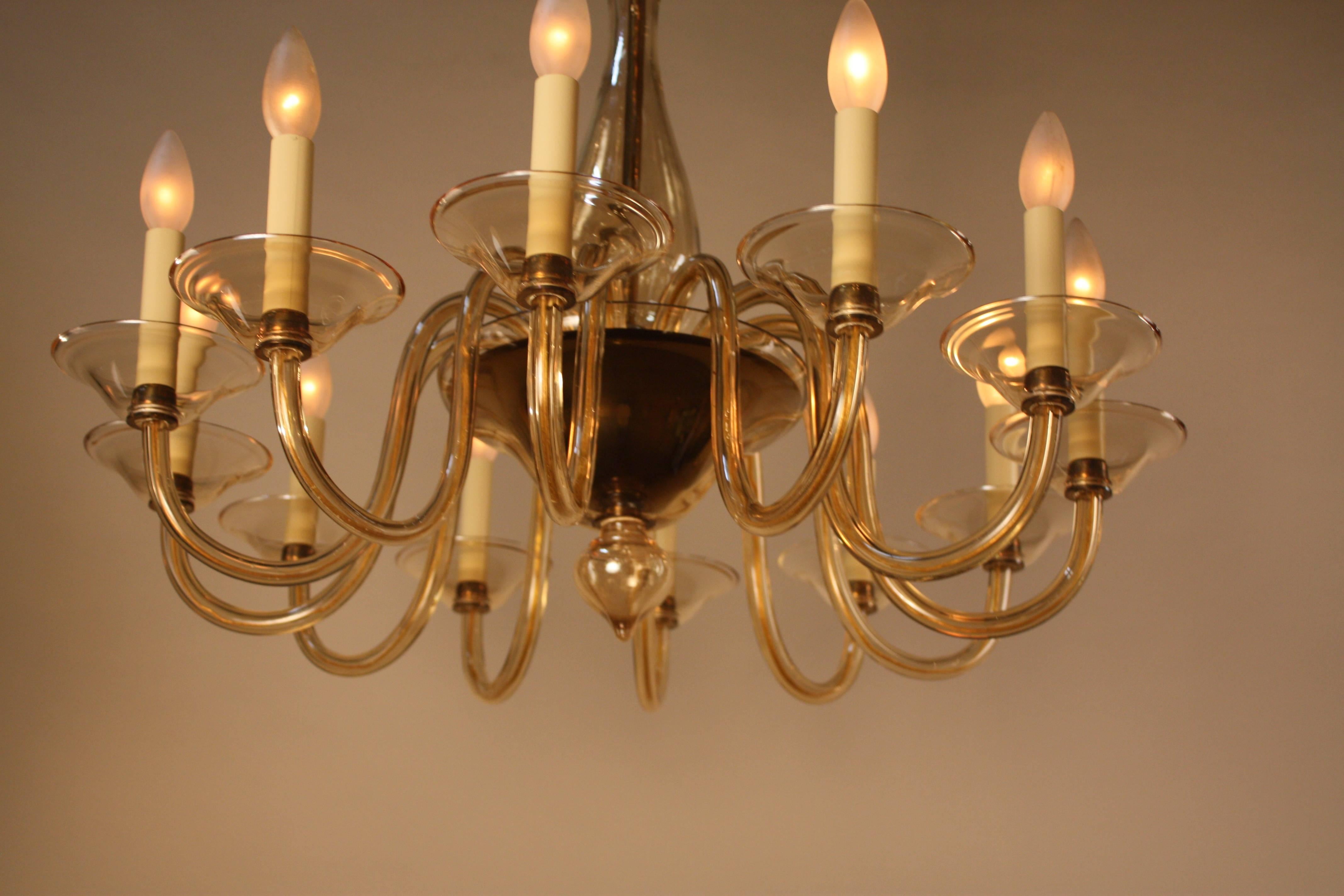 A handblown glass chandelier made of famed Murano glass. Simple yet elegant, this twelve-light piece is in a champagne color and dates from the 1970s. 
The minimum height fully installed is 30