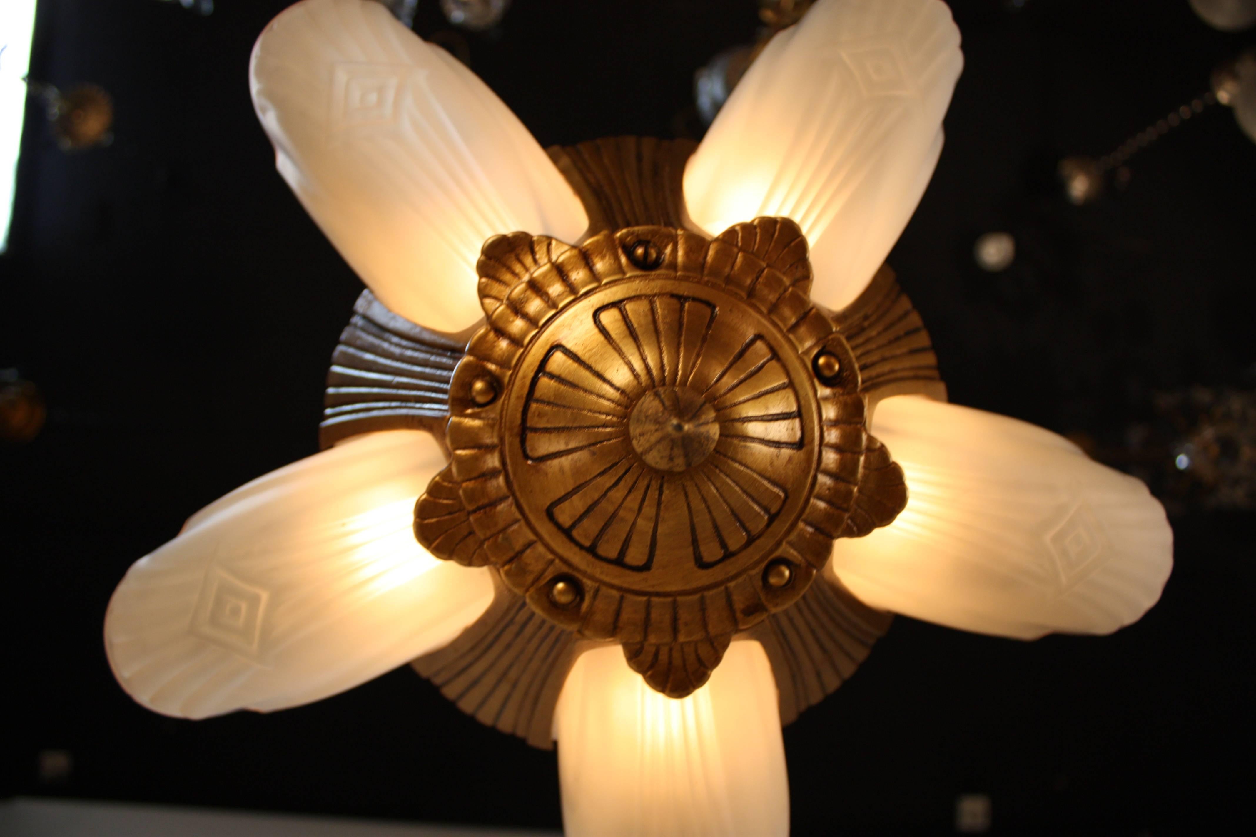 Lustre Art Déco américain à cinq lumières encastrées. Le cadre est fini en or et les abat-jour en verre clair givré.