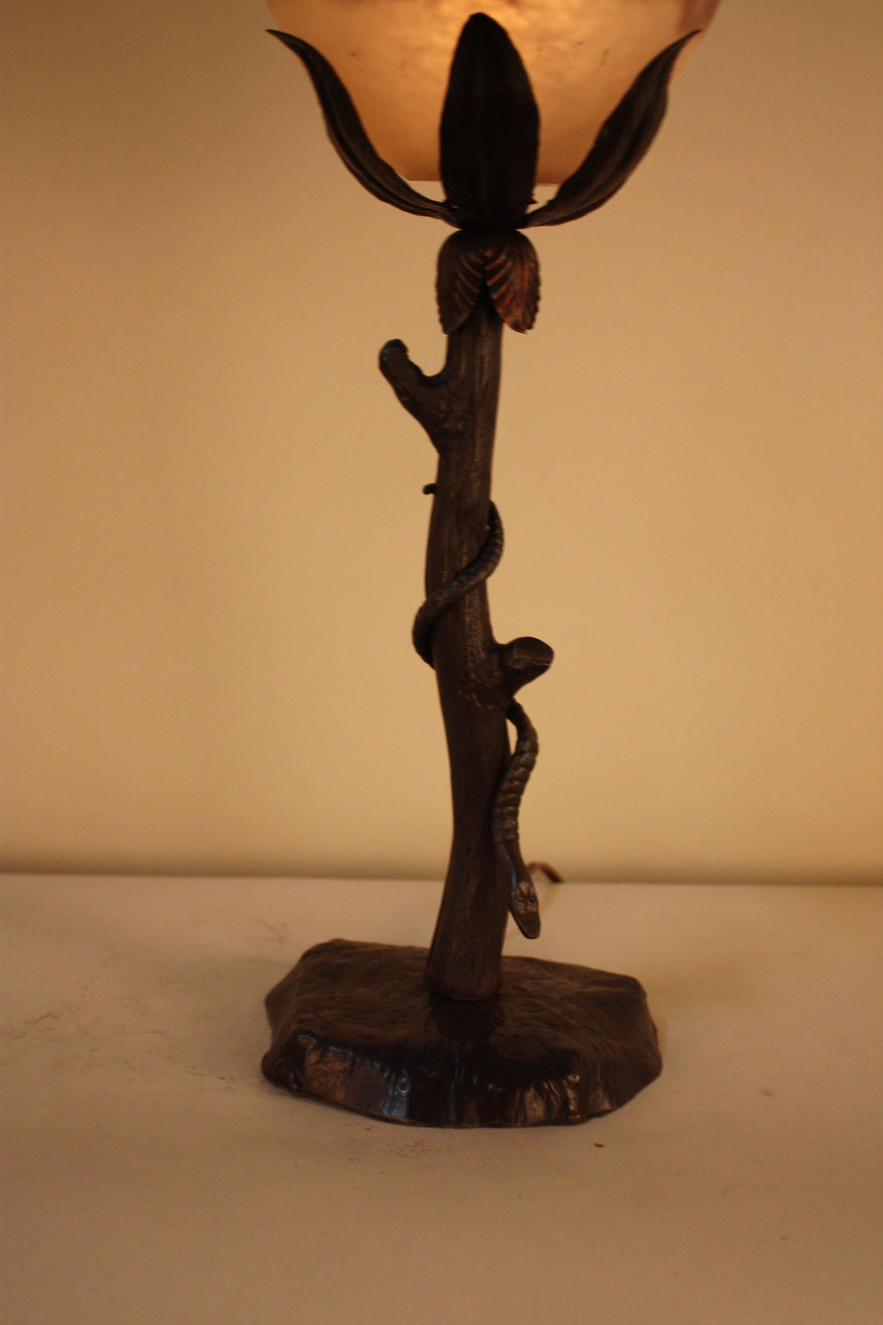 Handmade wrought iron base with snake lowering from the tree and blown glass shade table lamp.