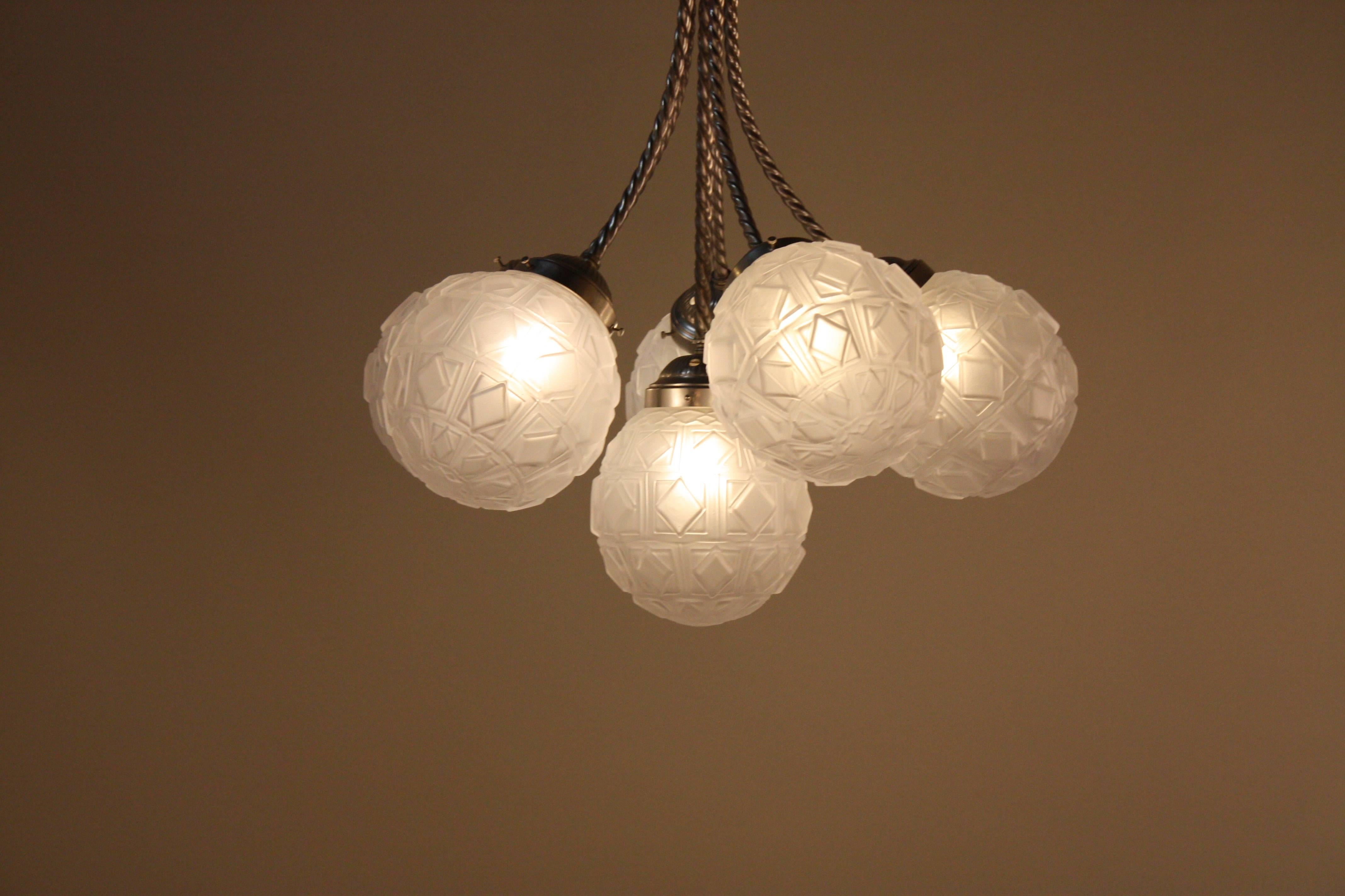 French 1930s nickel on bronze chandelier with six geometric design glass globe shades.
Six lights 60watts each.