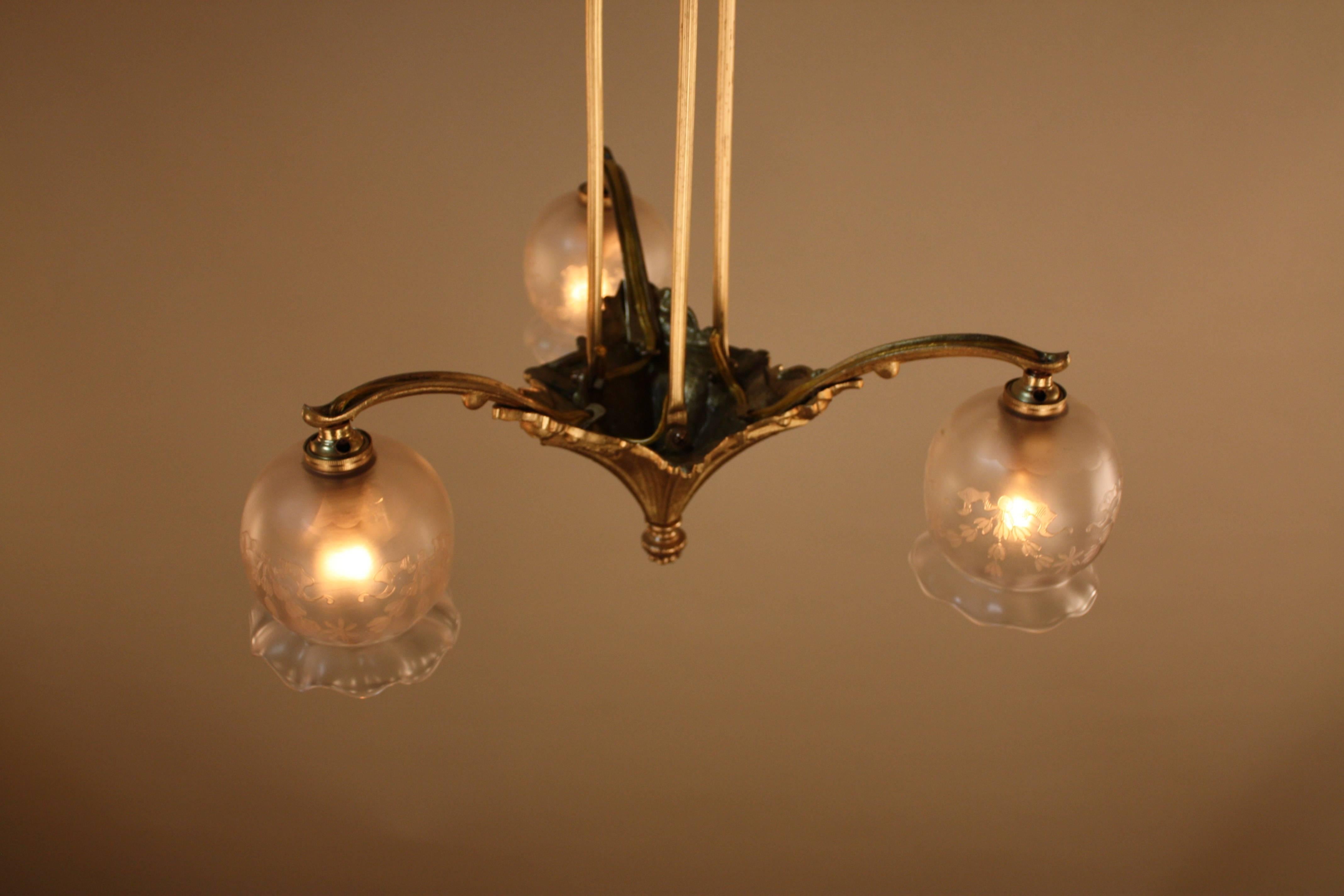 French, 1920s three-light bronze chandelier with etched glass shades.
