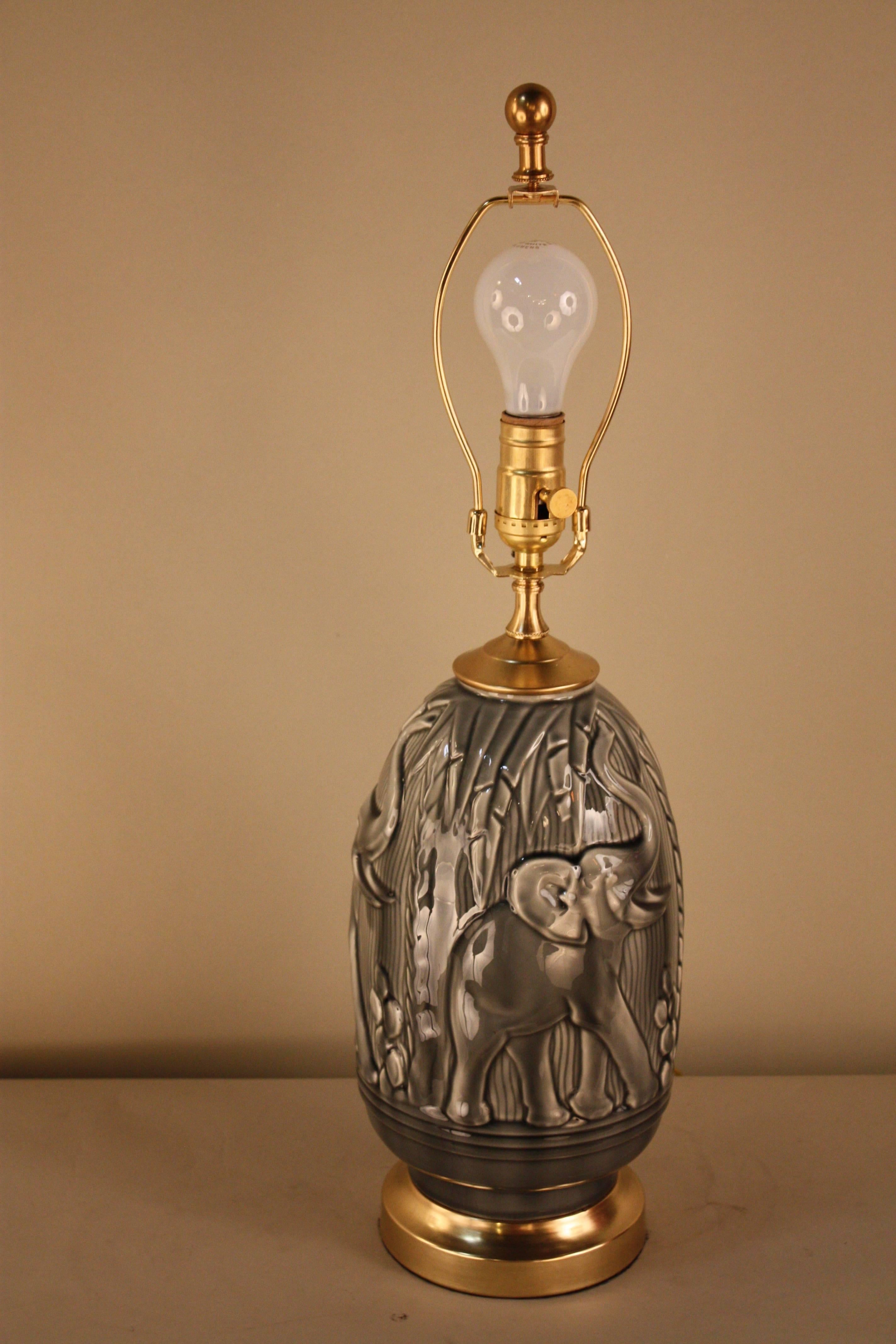 Elegant high glazed gray pottery table lamp with running elephant motif.