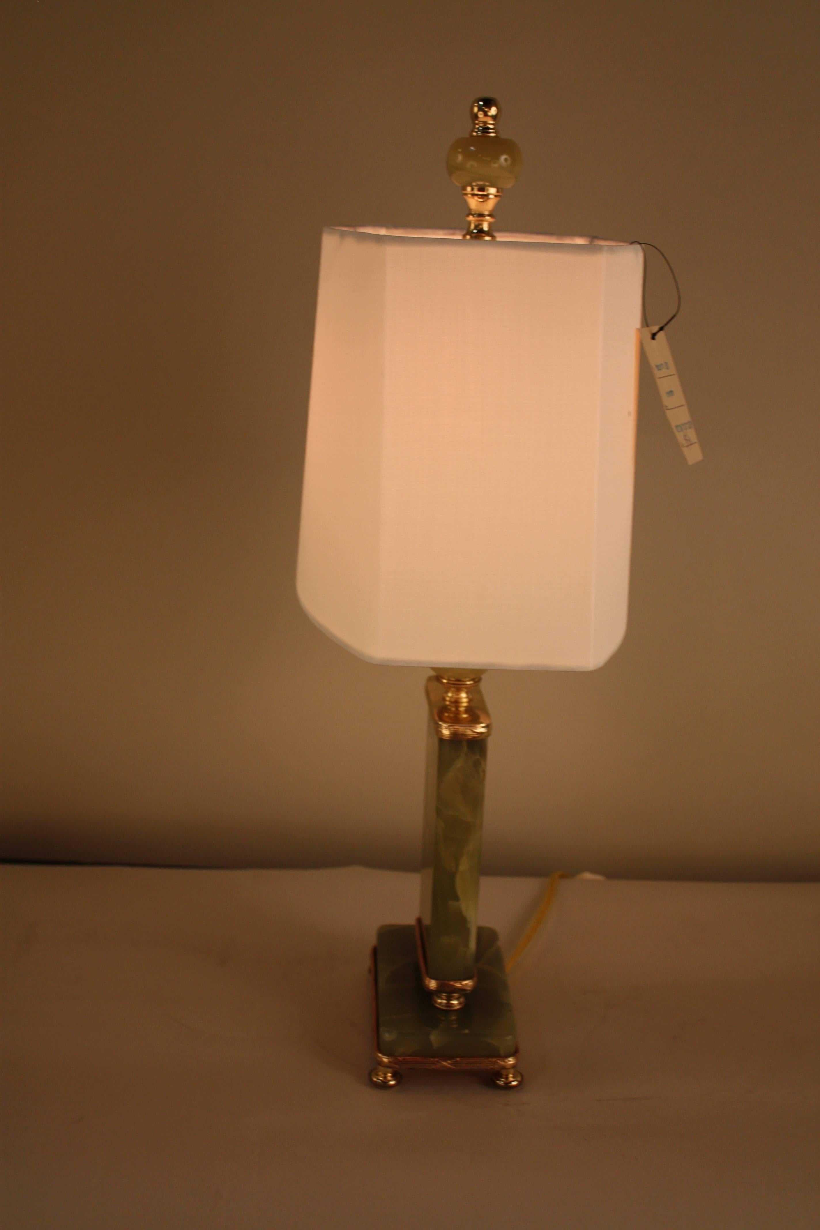 A fantastic American Art Deco table lamp. Beautiful textured green onyx framed in polished brass with cut corner oval shape silk lampshade.