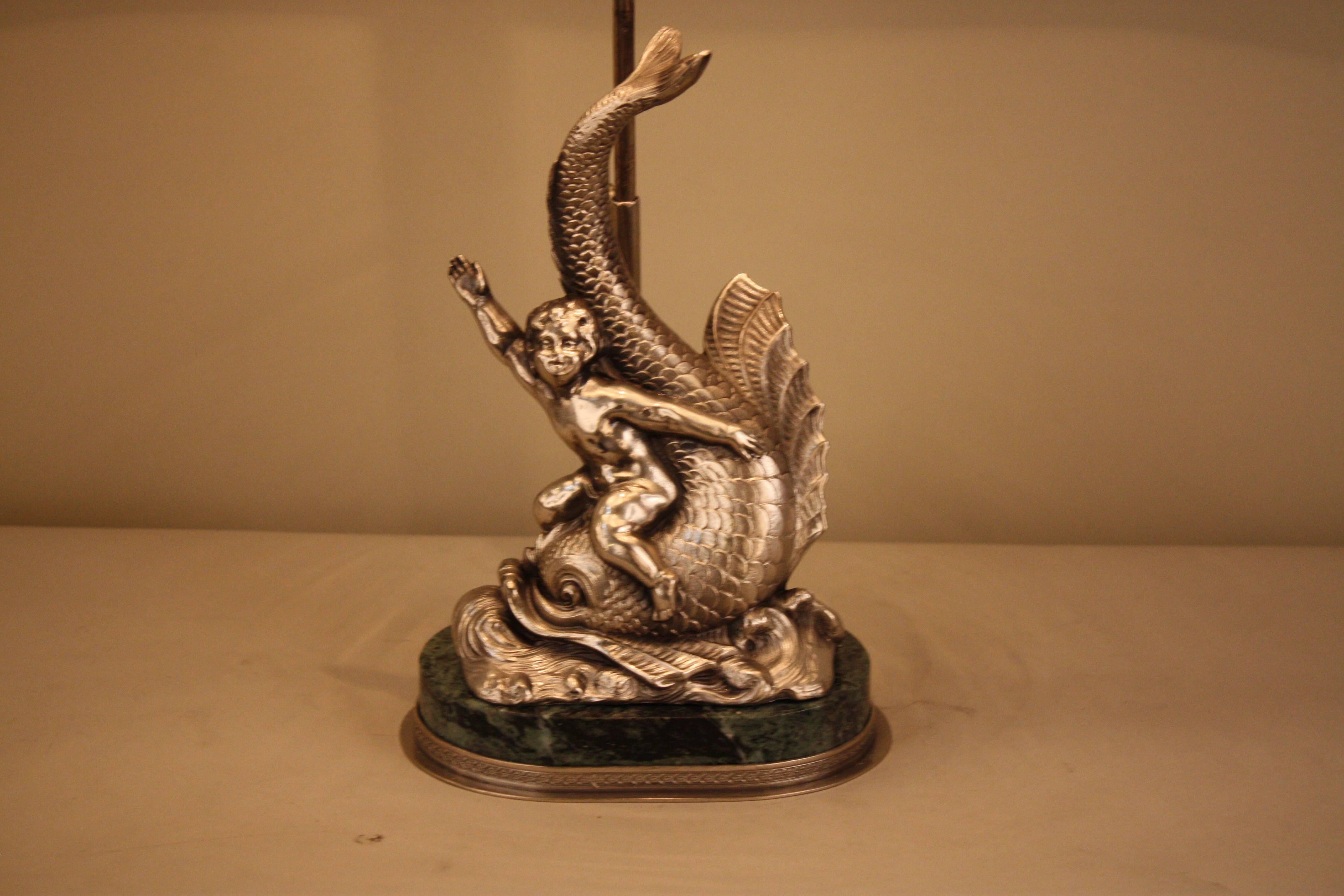 Early 20th century statue in form of a boy on a swimming dolphin that has been made to a table lamp.