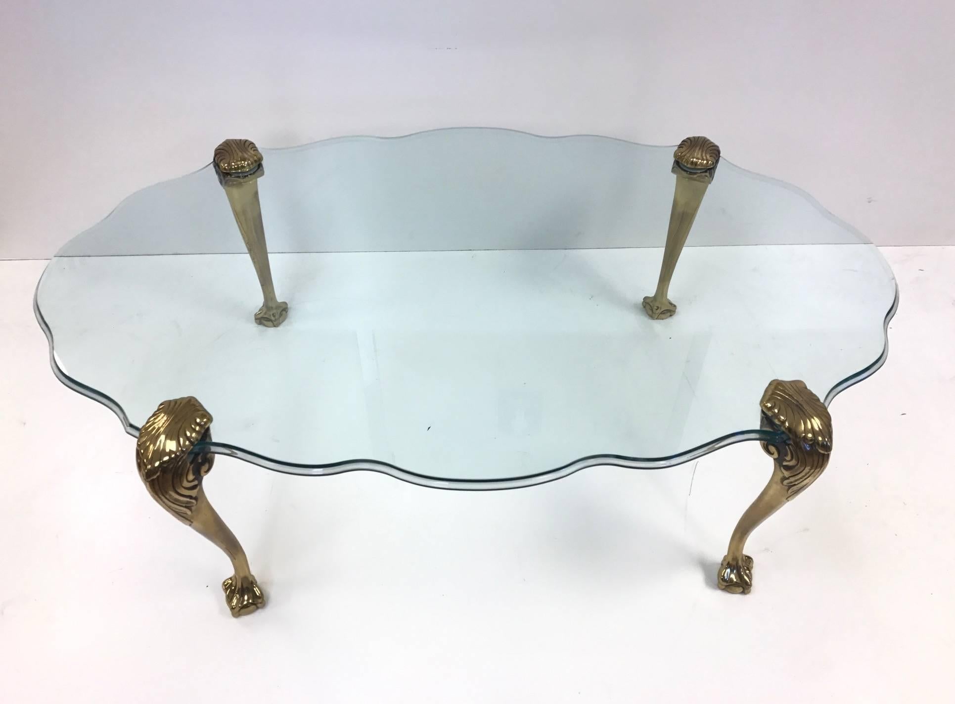 Brass claw and ball glass top coffee table. Heavy solid brass legs with a scalloped edge bevelled glass.