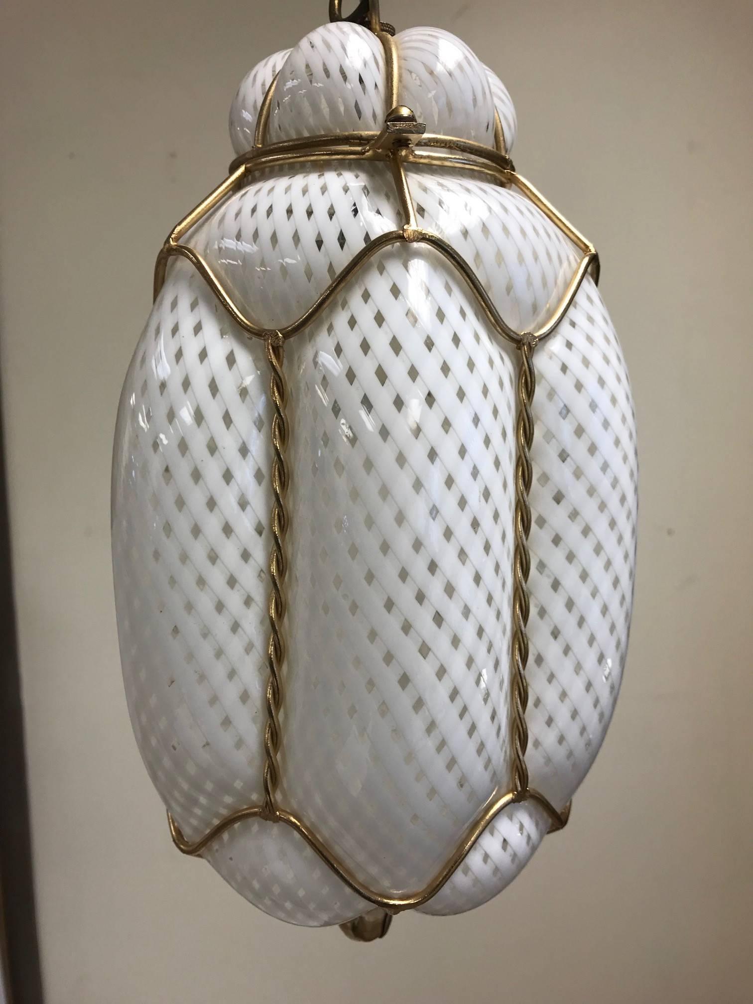 Seguso Murano handblown light pendant / fixture. White and clear Murano glass with a decorative brass cage trim. Style of Dino Martens.
Measures: 36H (includes pendant and chain). Murano pendant itself: 13 H x 7 W.