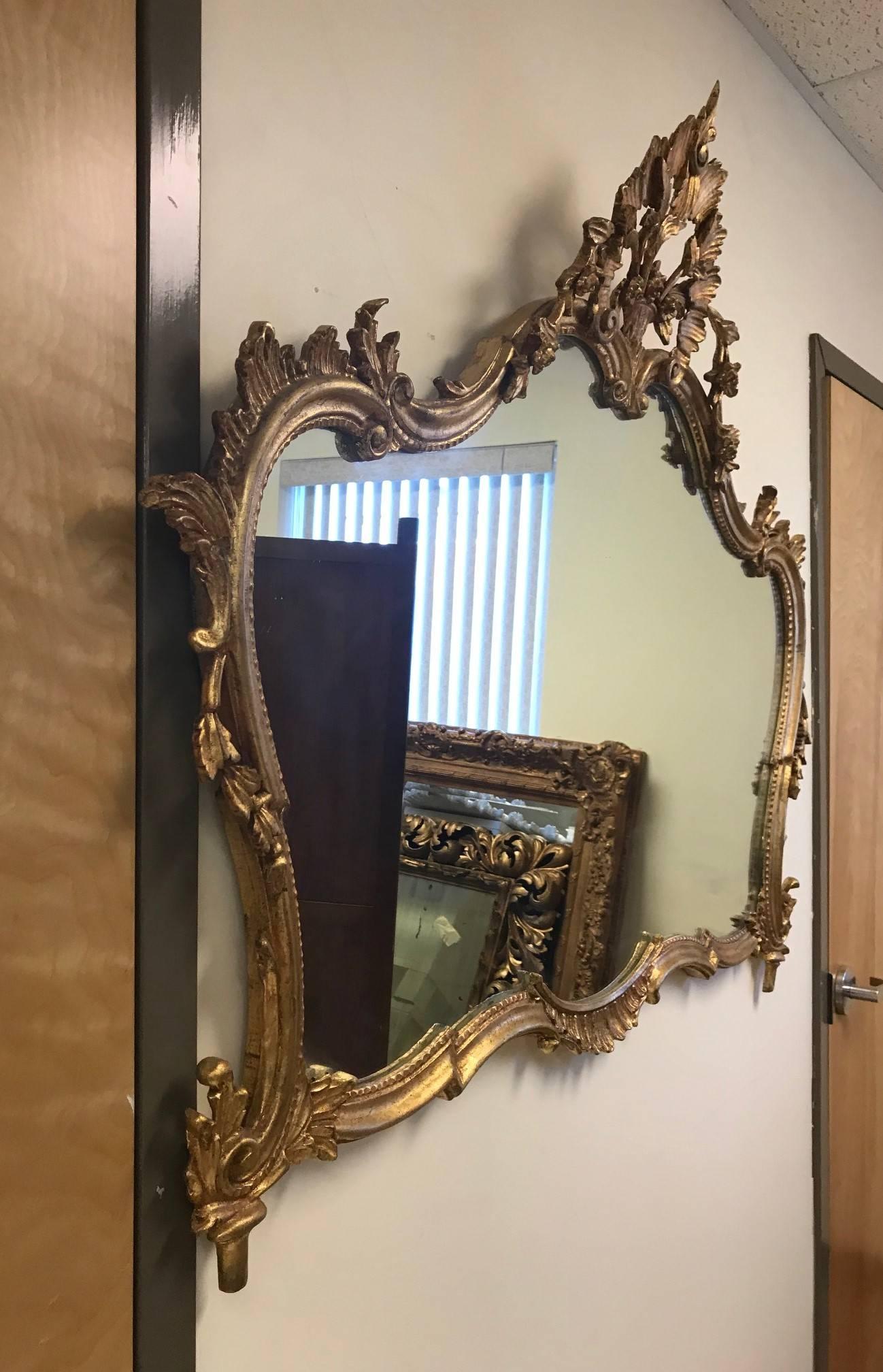 1920s, Italian giltwood mirror with decorative, carved wood frame. Gold leaf.