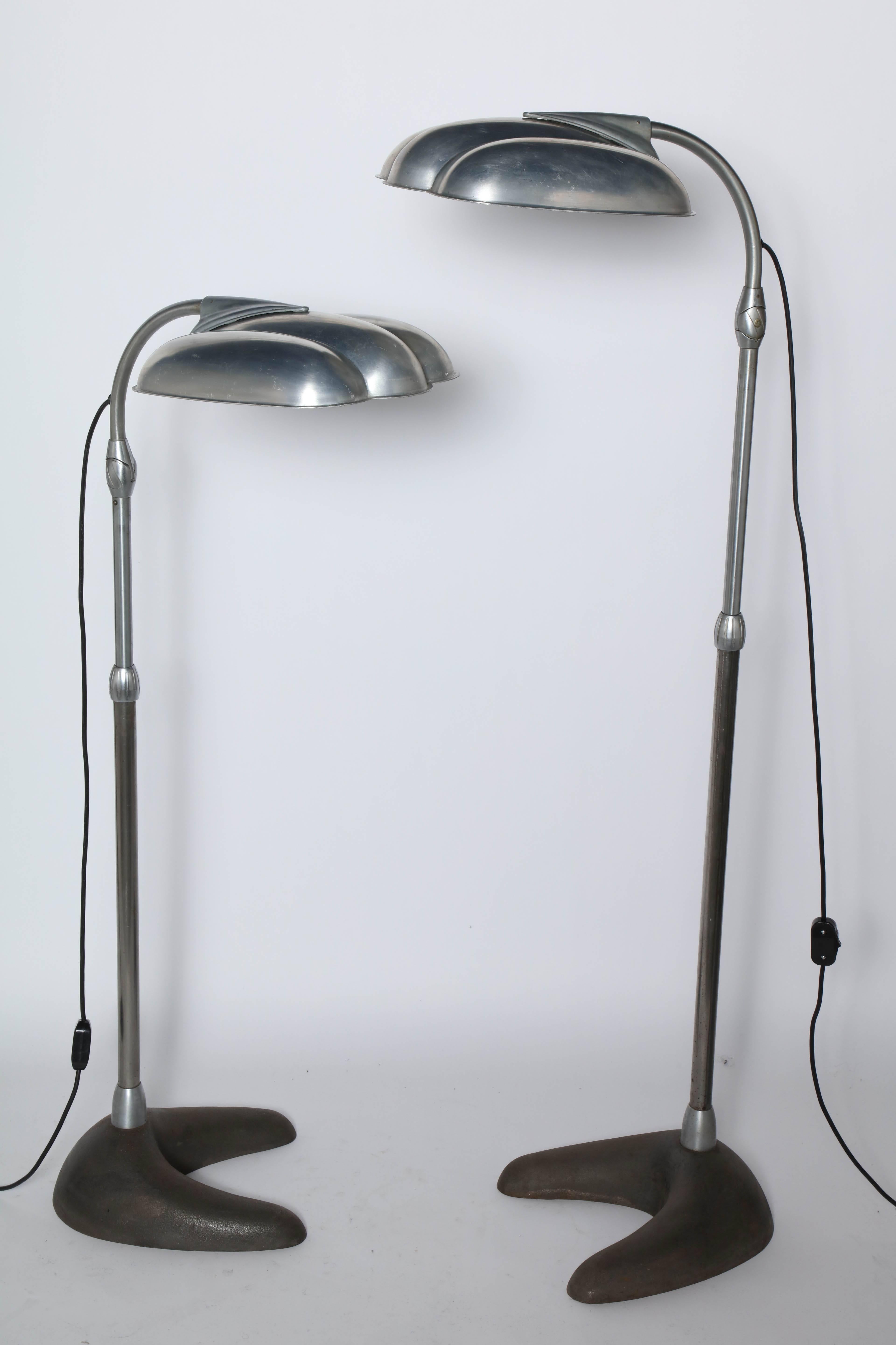Pair of Sperti Sunlamp Inc. adjustable, repurposed light therapy Floor Lamps in the style of Raymond Loewy. Featuring articulating machined grooved Clam Shell Aluminum Reflector Shades, tilting lamp head, extension rod on heavy Dark Cast Iron