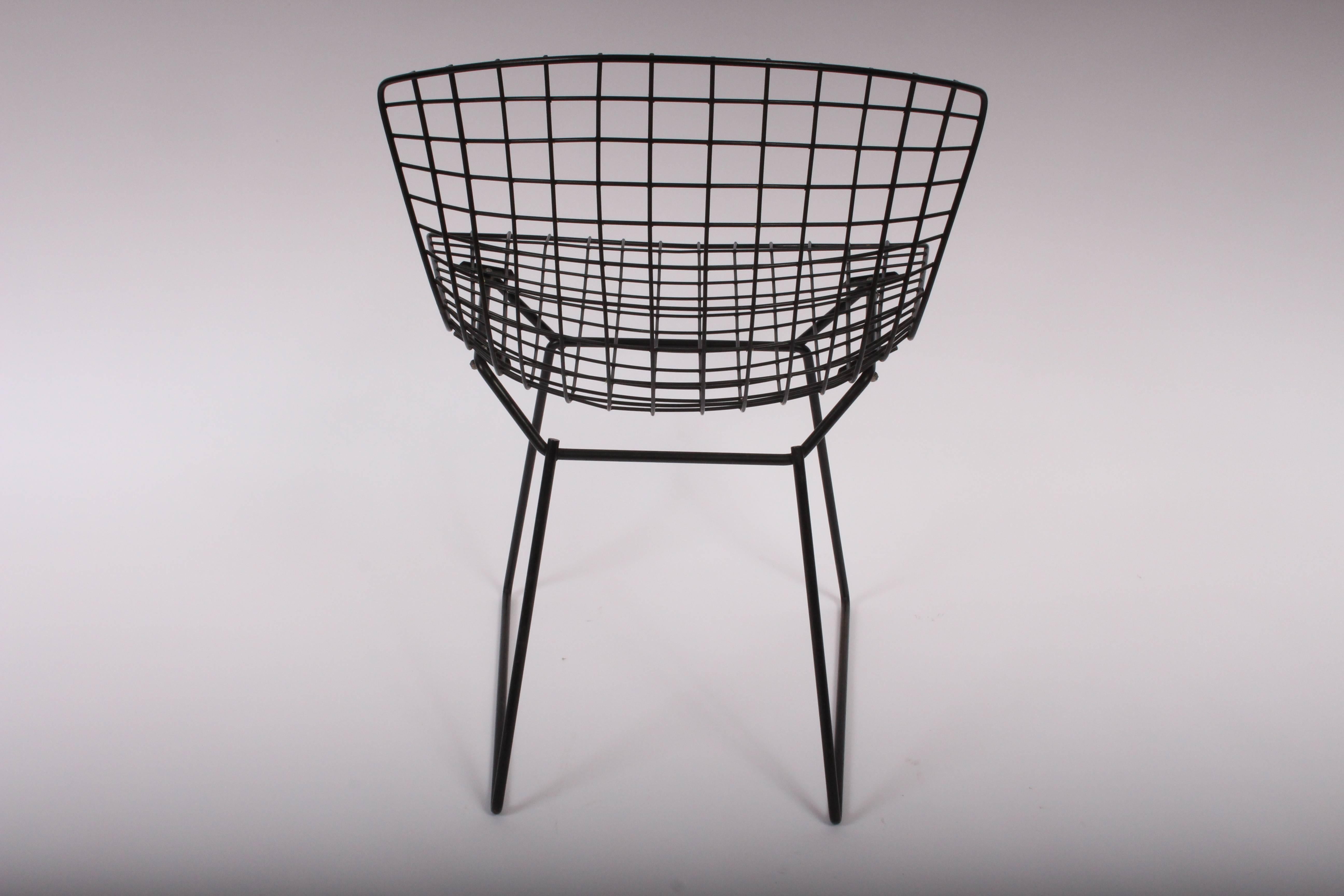 Early set of 4 Harry Bertoia for Knoll indoor outdoor black wire dining chairs with 2 piece chair pads. Featuring enameled black wire frame with original two-piece black vinyl seat and back cushions. Foam needs replacement. Most vinyl covers include