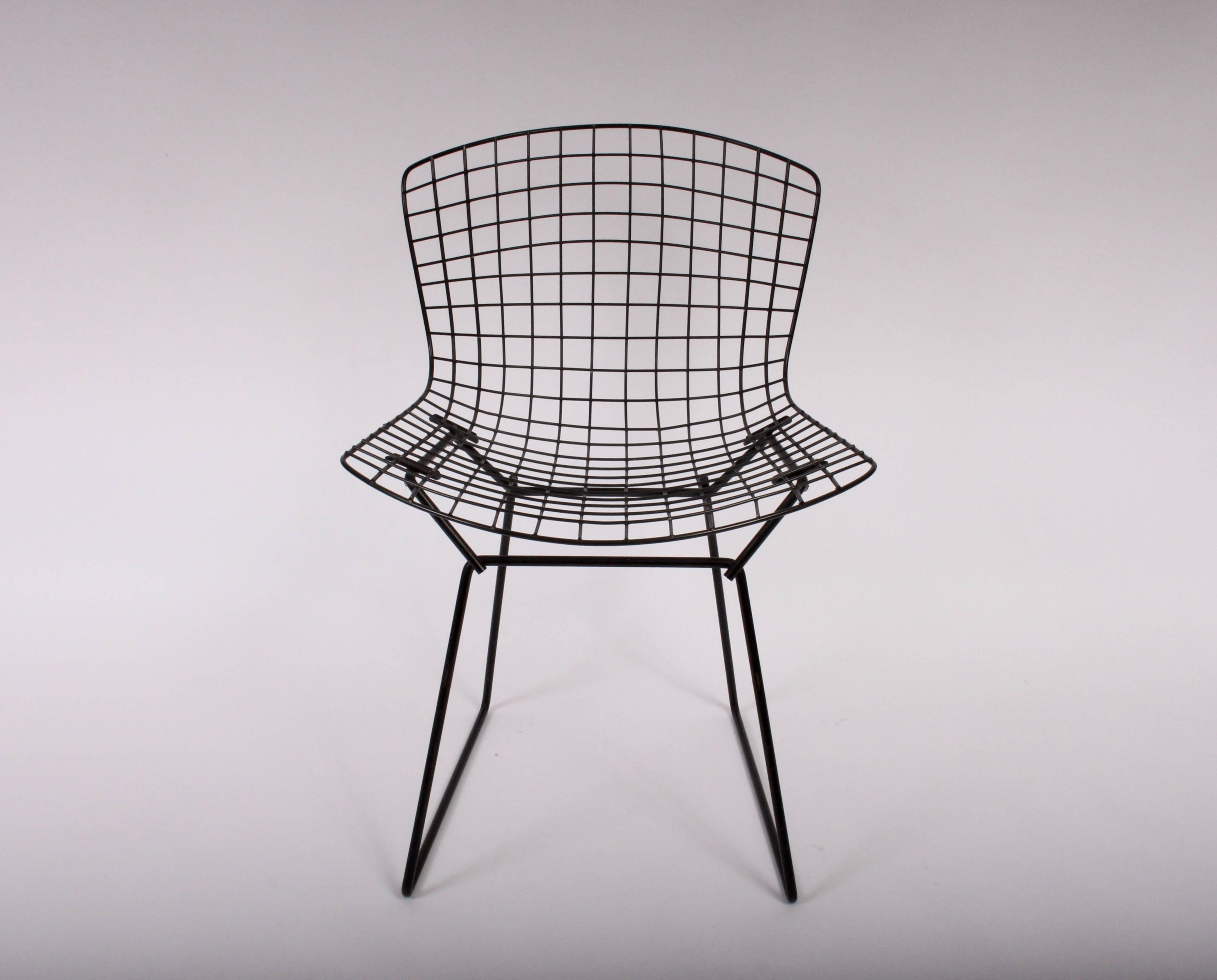Early set of twelve Harry Bertoia for Knoll indoor outdoor black wire dining chairs with 2-piece chair pads. Featuring classic enameled black wire frame with original two-piece black vinyl seat and back cushions. Foam needs replacement. Most vinyl