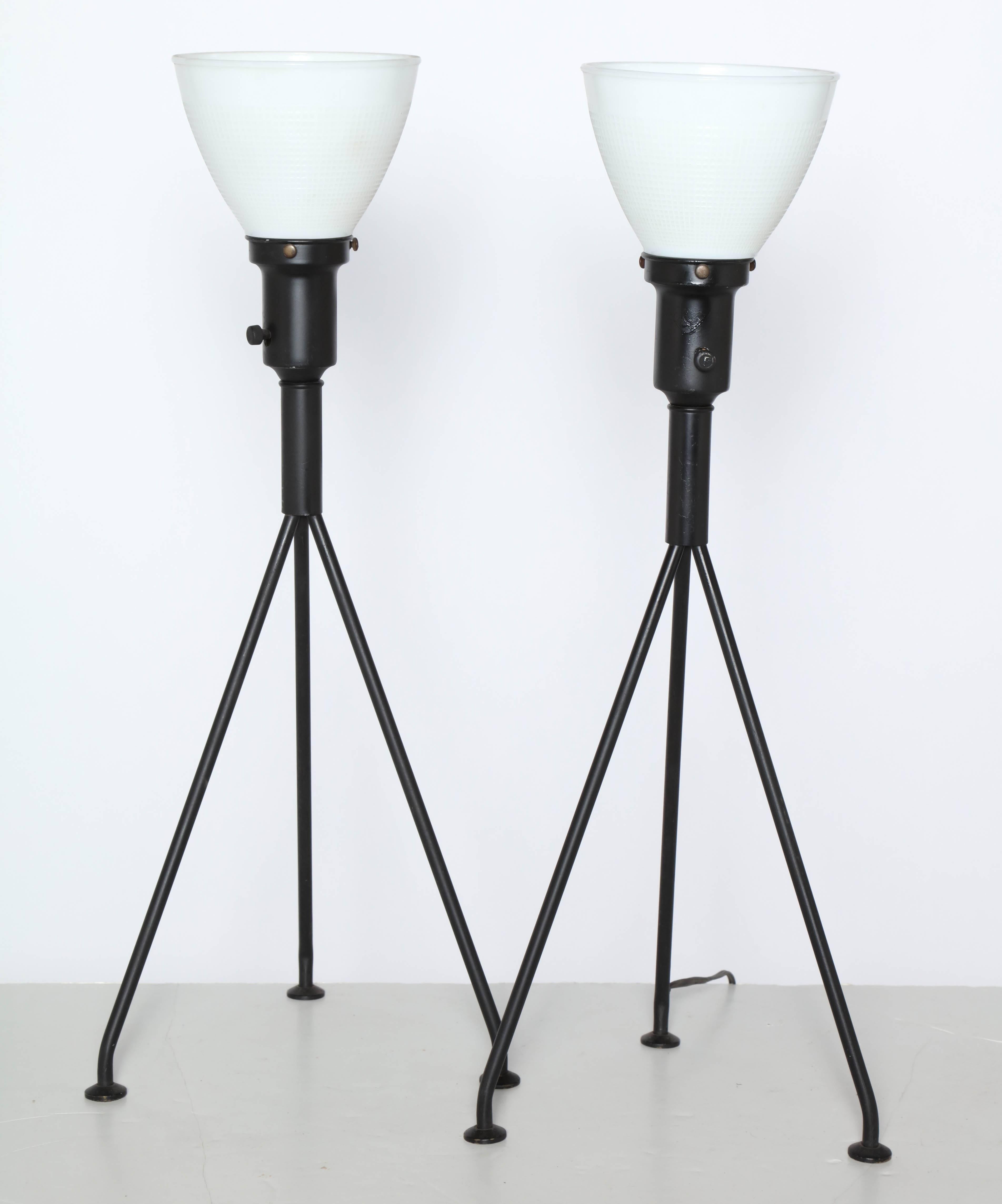 Pair of Gerald Thurston for Lightolier black and white table lamps, 1950s. Featuring balanced black enameled steel tripod legs, socket and neck, white milk glass liner shades atop rounded brass feet. For use with liner shades, with or without lamp