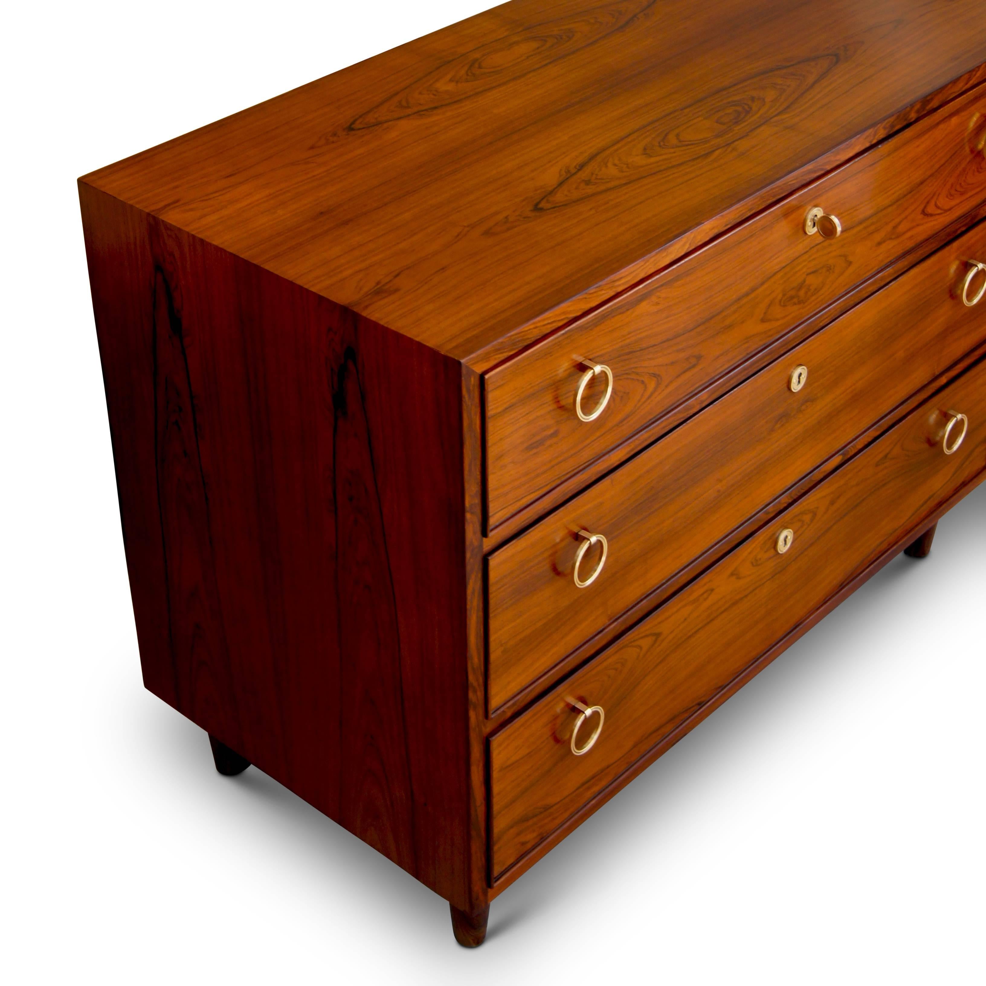 Extraordinary chest of drawers designed by architect and furniture designer Ernst Kuhn (1890-1948), using very handsome cuts of graphically figured wood, possibly walnut, and having  three drawers articulated in bead molding and double brass ring